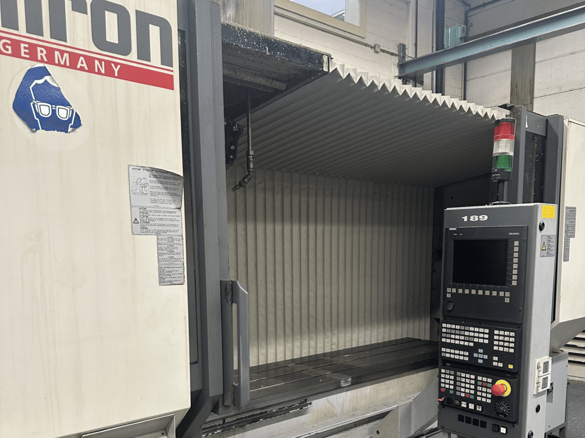 Alt text: Pohled zepředu na CNC stroj Hermle s ovládacím panelem s tlačítky a displejem, s otevřeným pracovním prostorem.