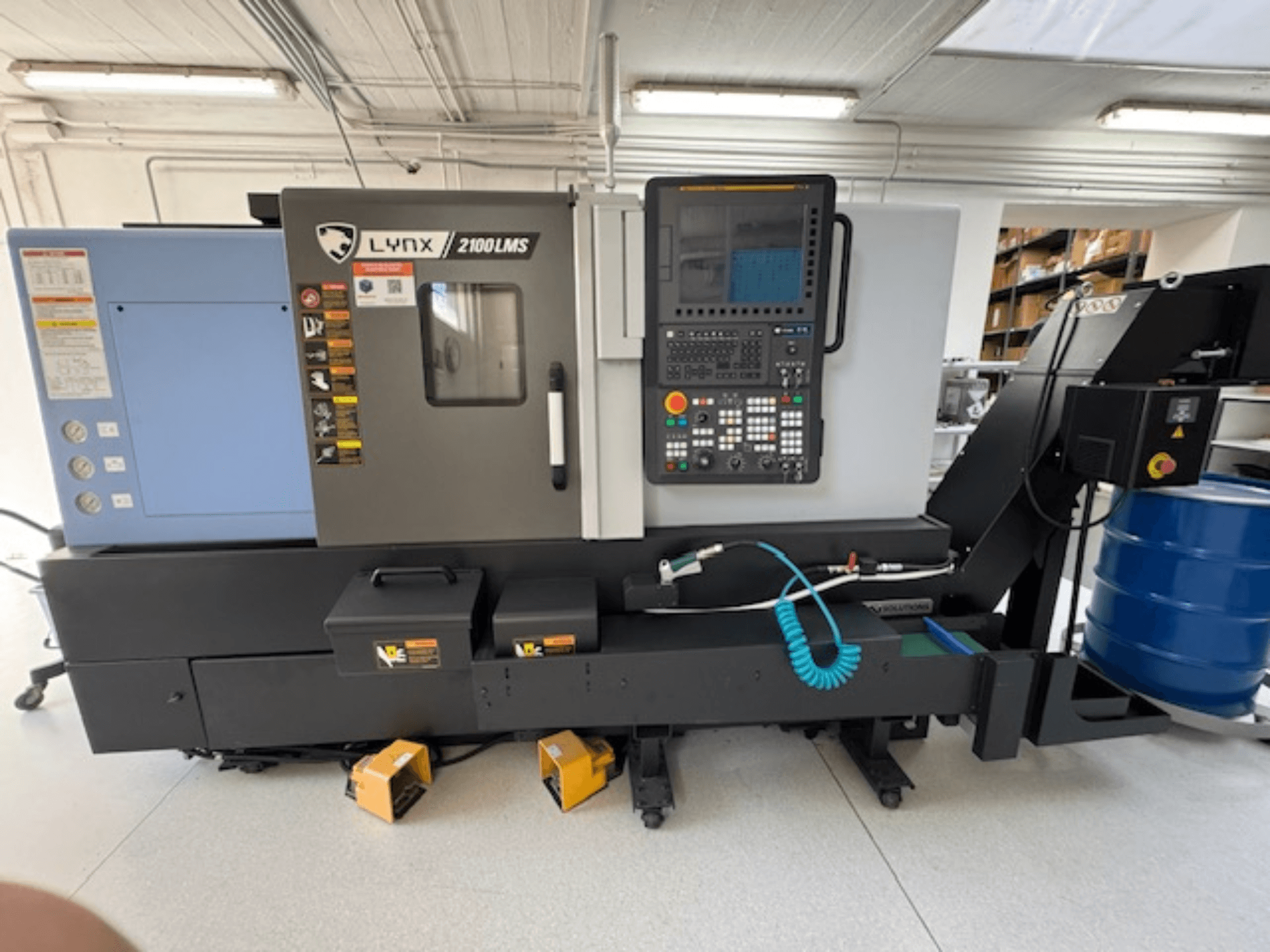 Horizontální soustruh DOOSAN LYNX 2100LMSA, pohled zepředu, s ovládacím panelem, hadicí chladicí kapaliny a úložnými boxy.