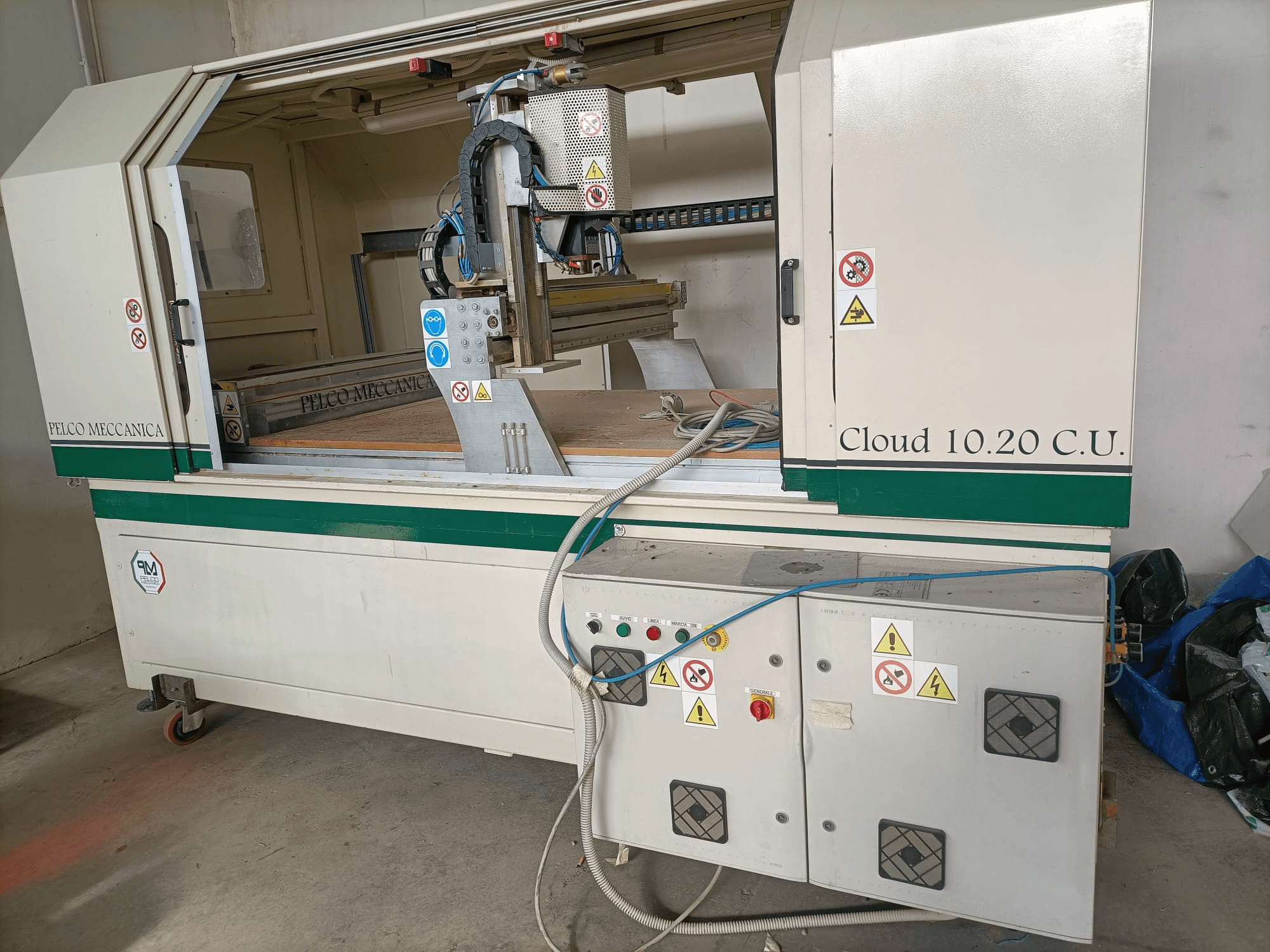 CNC frézka MECCANICA CLOUD 10.20 C.U., pohled zepředu na ovládací panel a pracovní prostor, s viditelnými bezpečnostními štítky a hadicemi.