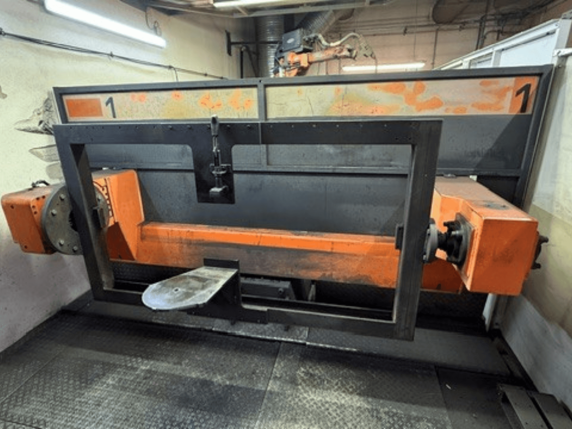 Pohled zepředu na svařovací buňku ABB IRB 2400L, na kterém je vidět velký robotický rám s oranžovými a černými součástmi v prostředí dílny.