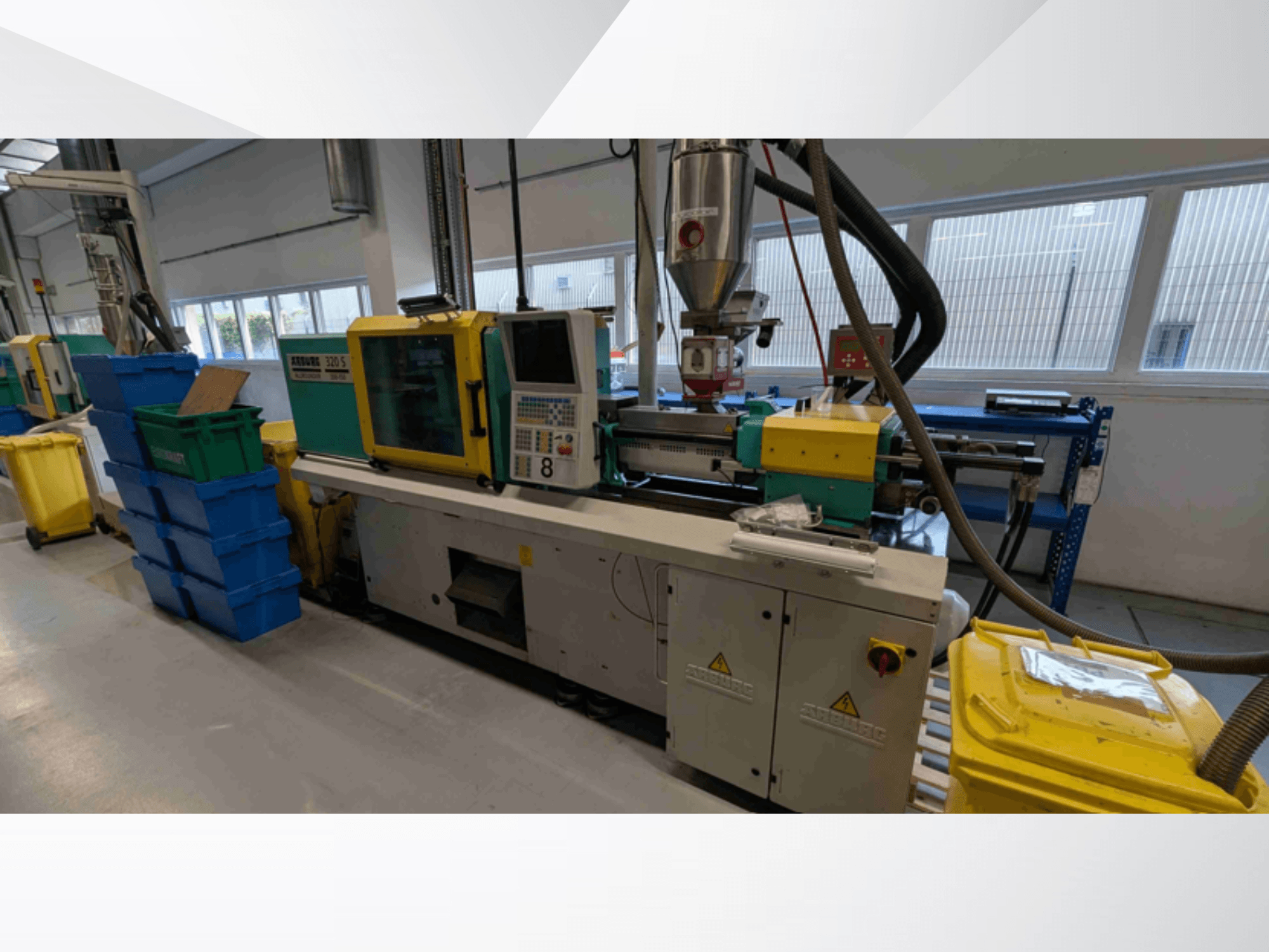 Hydraulický vstřikovací stroj Arburg 320 S 350-150, pohled zepředu, na kterém jsou vidět ovládací prvky, extrudér a zásobníky na barevný materiál.