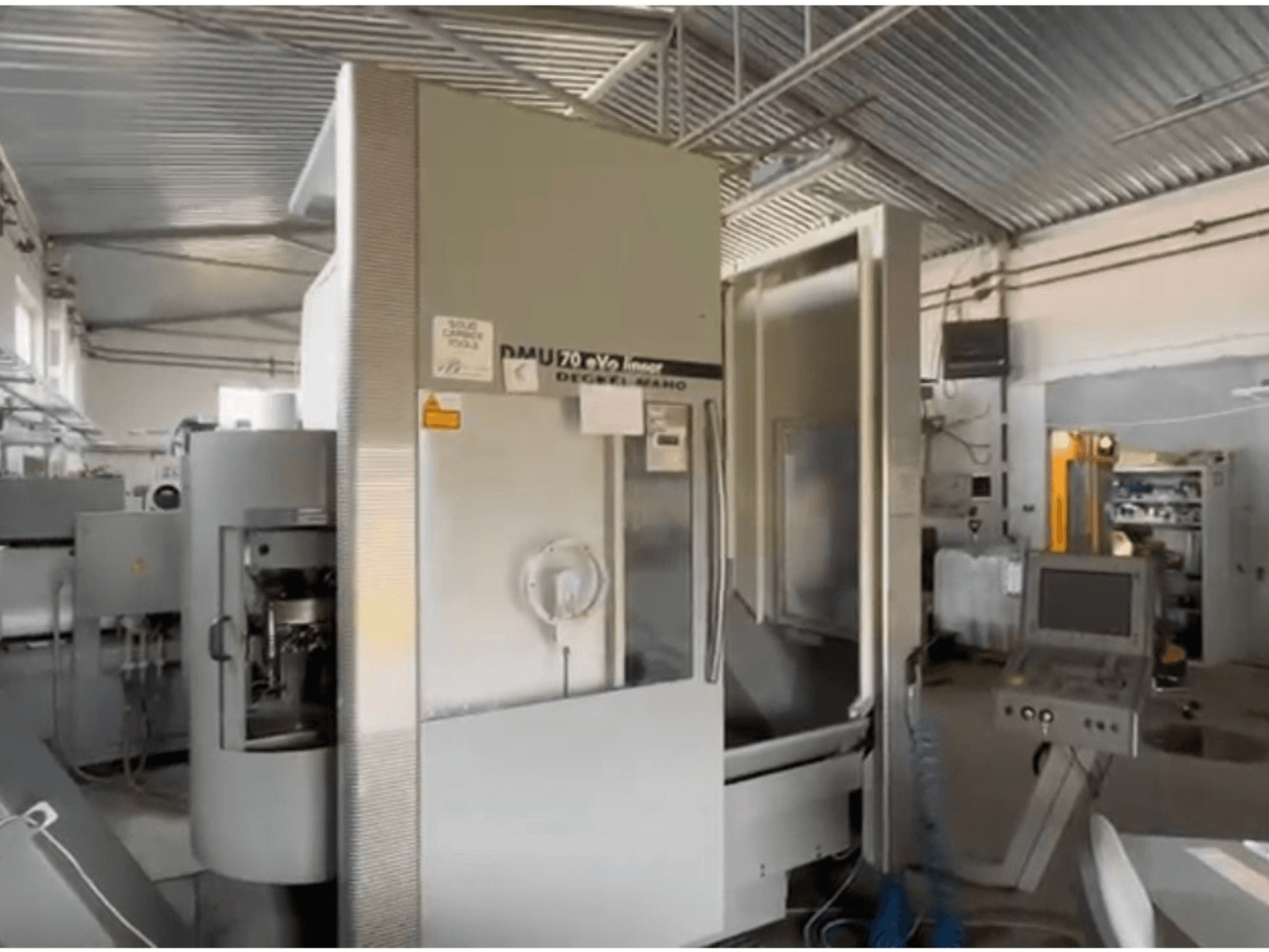 Lineární CNC stroj DMU 70 eVo v dílně, pohled zepředu, s ovládacím panelem a moderním designem.