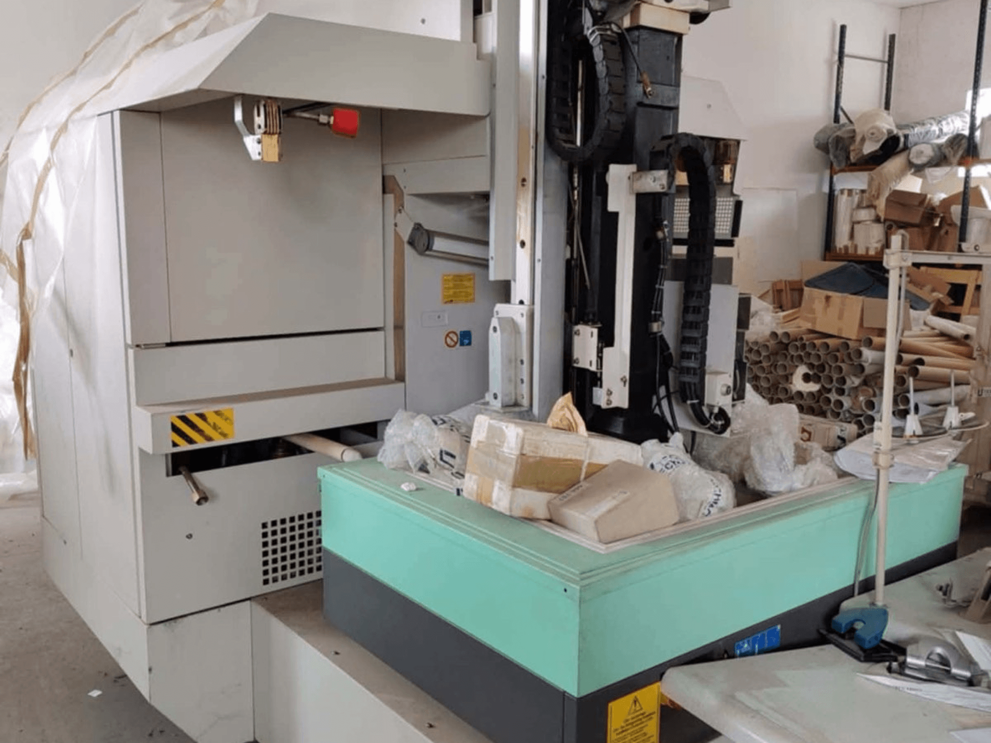 AGIE AGIETRON INTEGRAL 2 elektroerozivní stroj, pohled zepředu, ukazuje ovládací panel, pracovní stůl a okolní nepořádek.