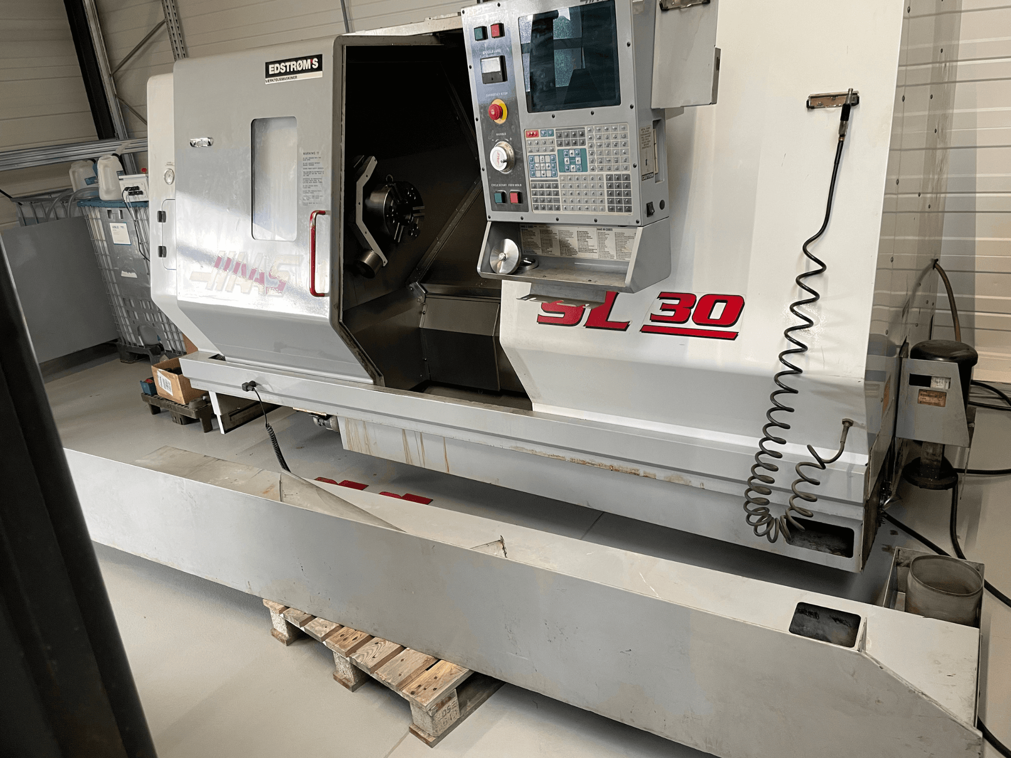 CNC soustruh Haas SL 30 v dílně, boční pohled, s ovládacím panelem a otevřeným vřetenem pro obrábění.