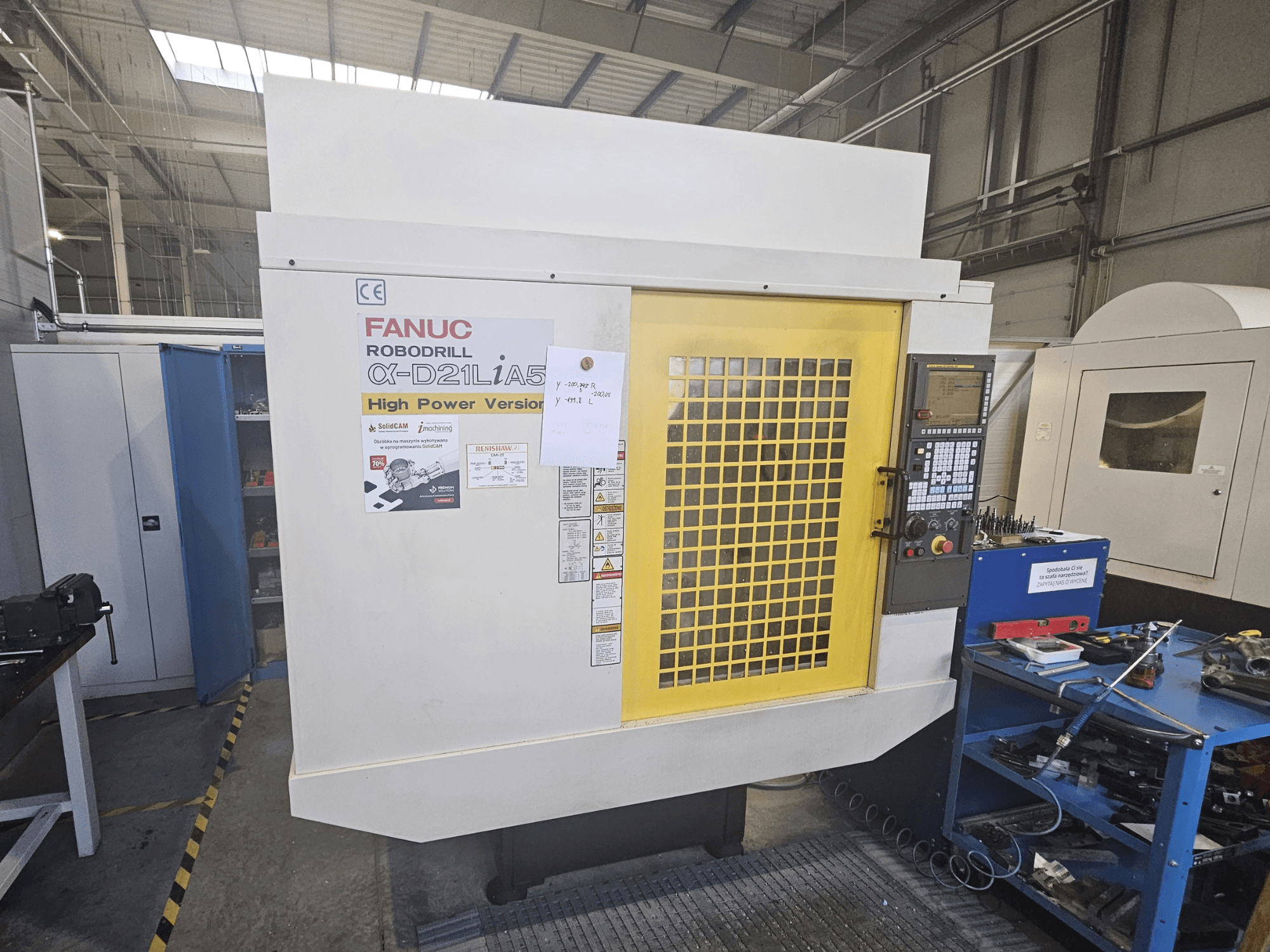 Pohled zepředu na vrtačku FANUC Robodrill α-D21LiA5 se žlutými bezpečnostními dvířky, ovládacím panelem a nástroji v blízkosti pracovního prostoru.