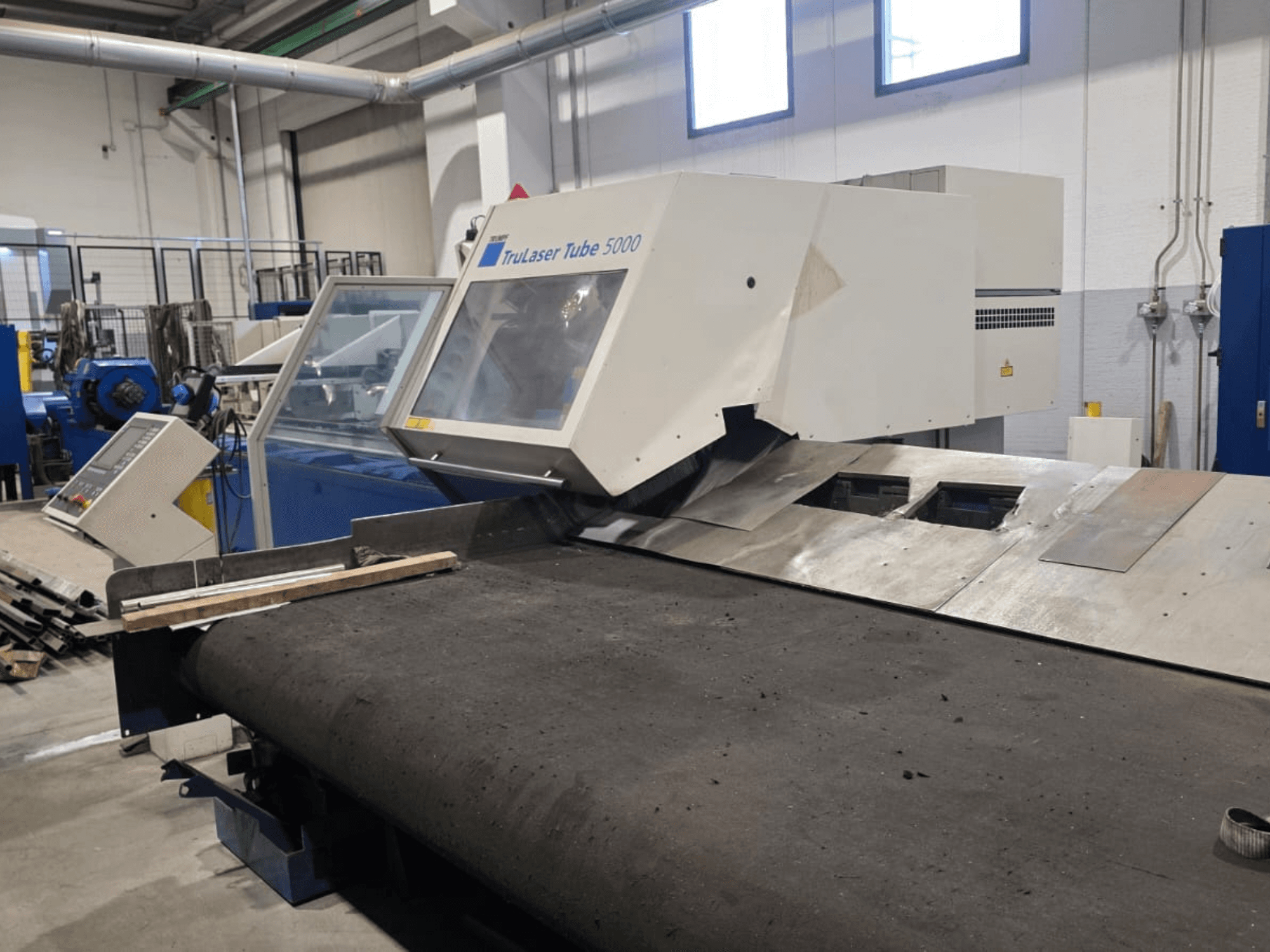 Stroj na řezání trubek TRUMPF LASERTUBE 5000, pohled zepředu, na kterém je vidět řezací oblast a ovládací panel.