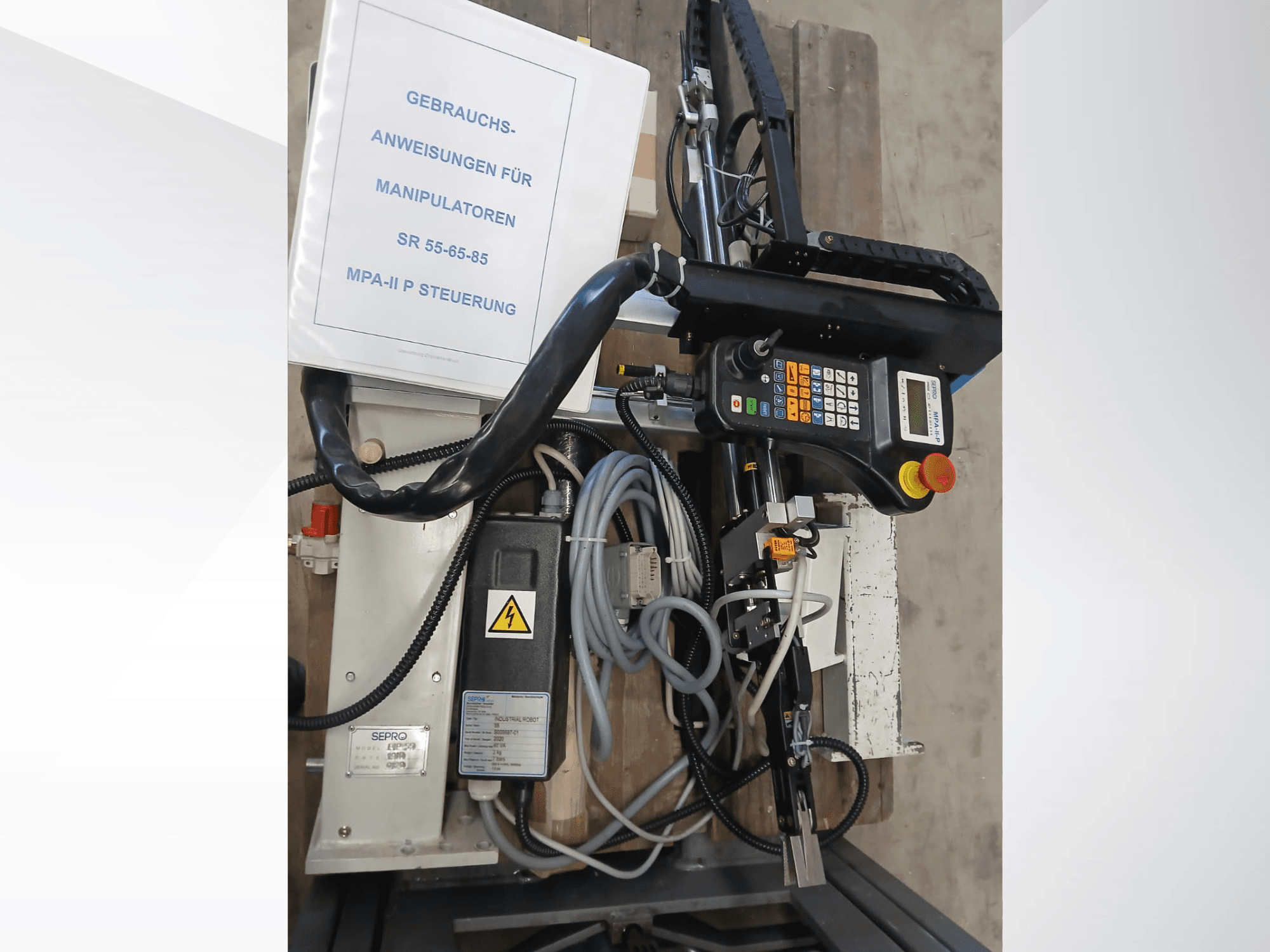 Ovládací panel a součásti portálového robota Sepro PIP-55, pohled z boku, s viditelnou uživatelskou příručkou.