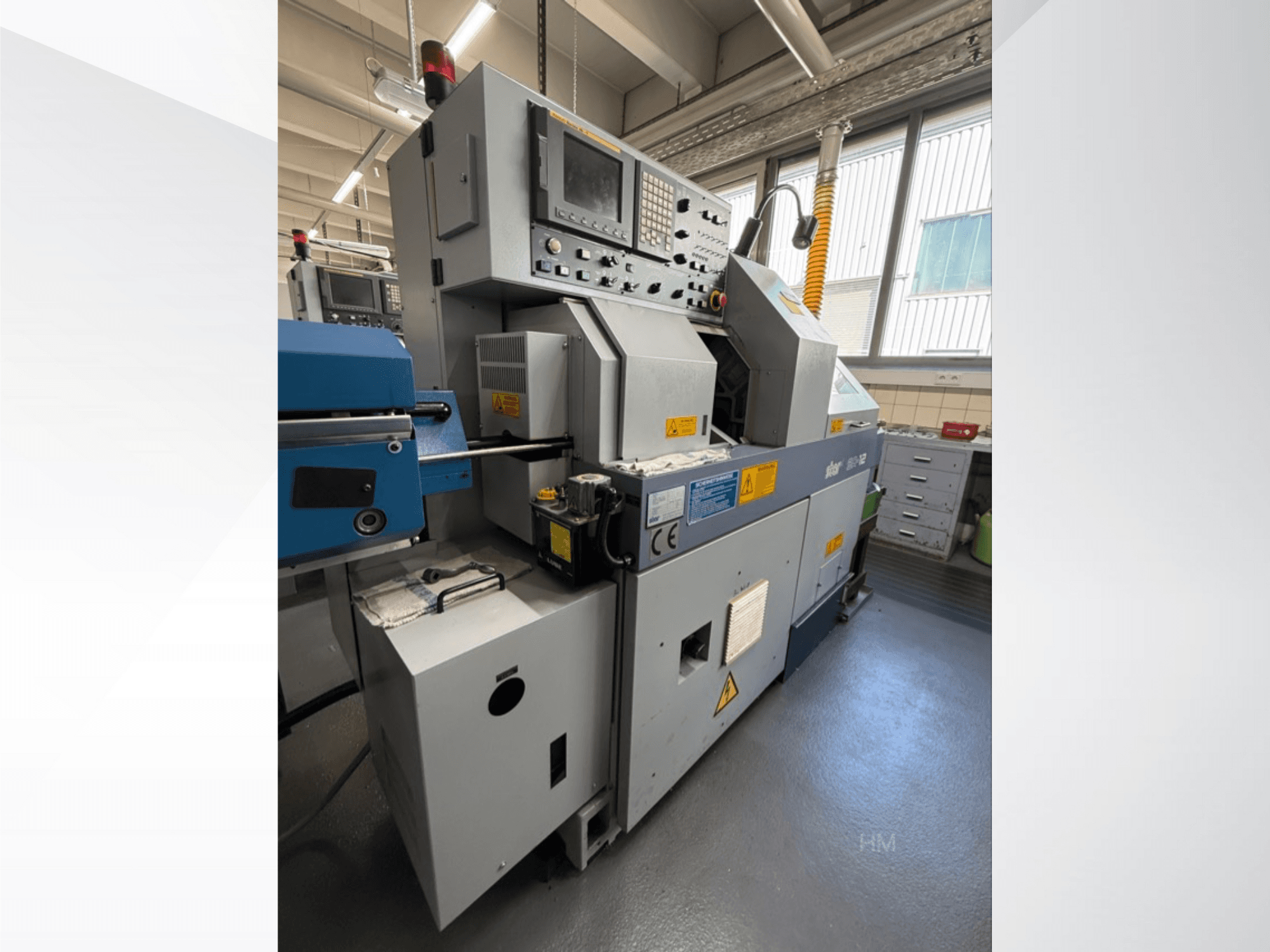 Pohled na stroj lithec 3231 zepředu, zobrazující ovládací panel, motor a modrou podávací část v dobře osvětleném průmyslovém prostředí.