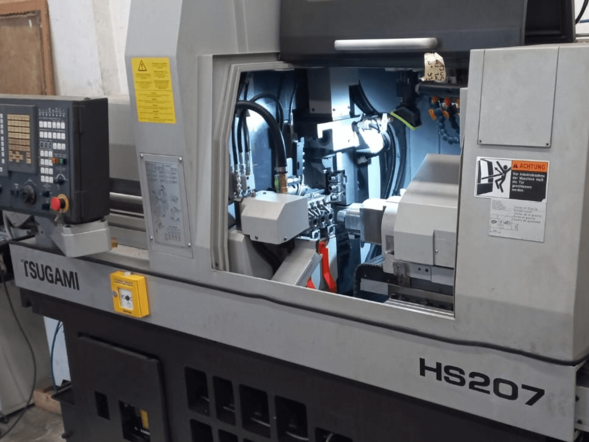 Švýcarský soustruh TSUGAMI HS207, pohled zepředu znázorňující ovládací panel a vnitřní součásti.