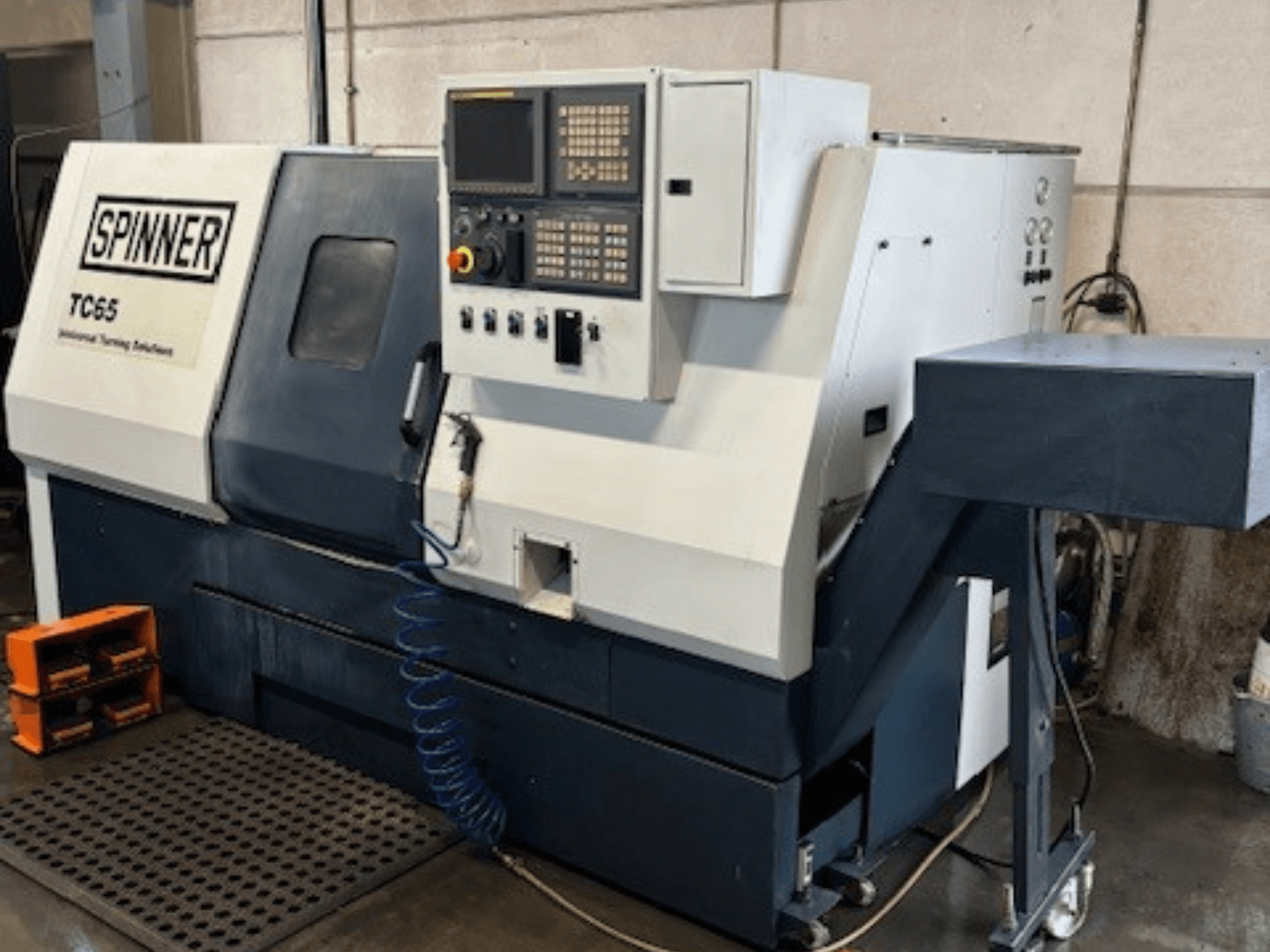 Průmyslový soustruh Spinner TC65, pohled zepředu, s ovládacím panelem, vedením stlačeného vzduchu a úložným prostorem pro nástroje.