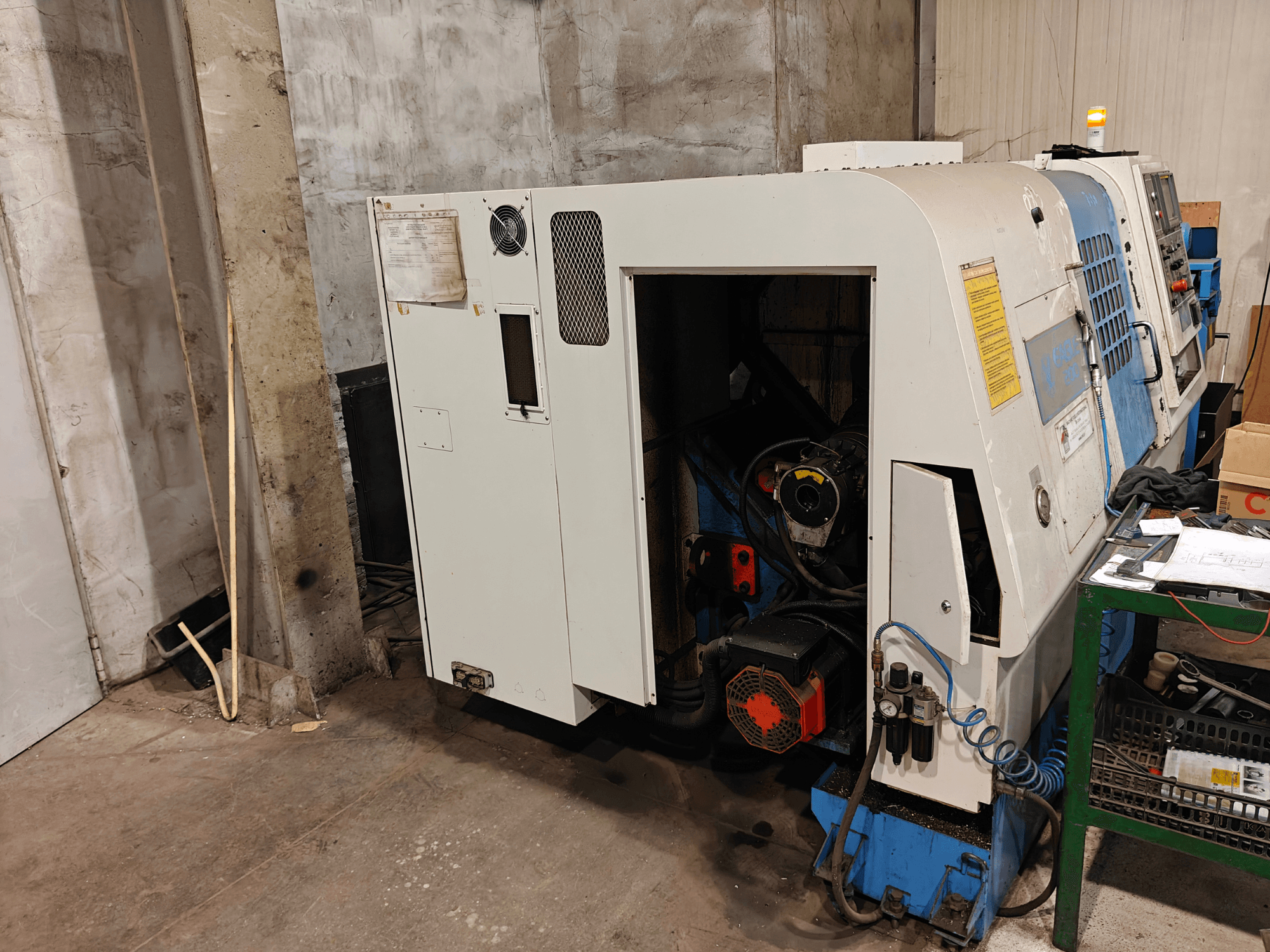 Pohled zepředu na soustruh, značka a model neuvedeny, s ovládacími prvky a viditelnými součástmi motoru.