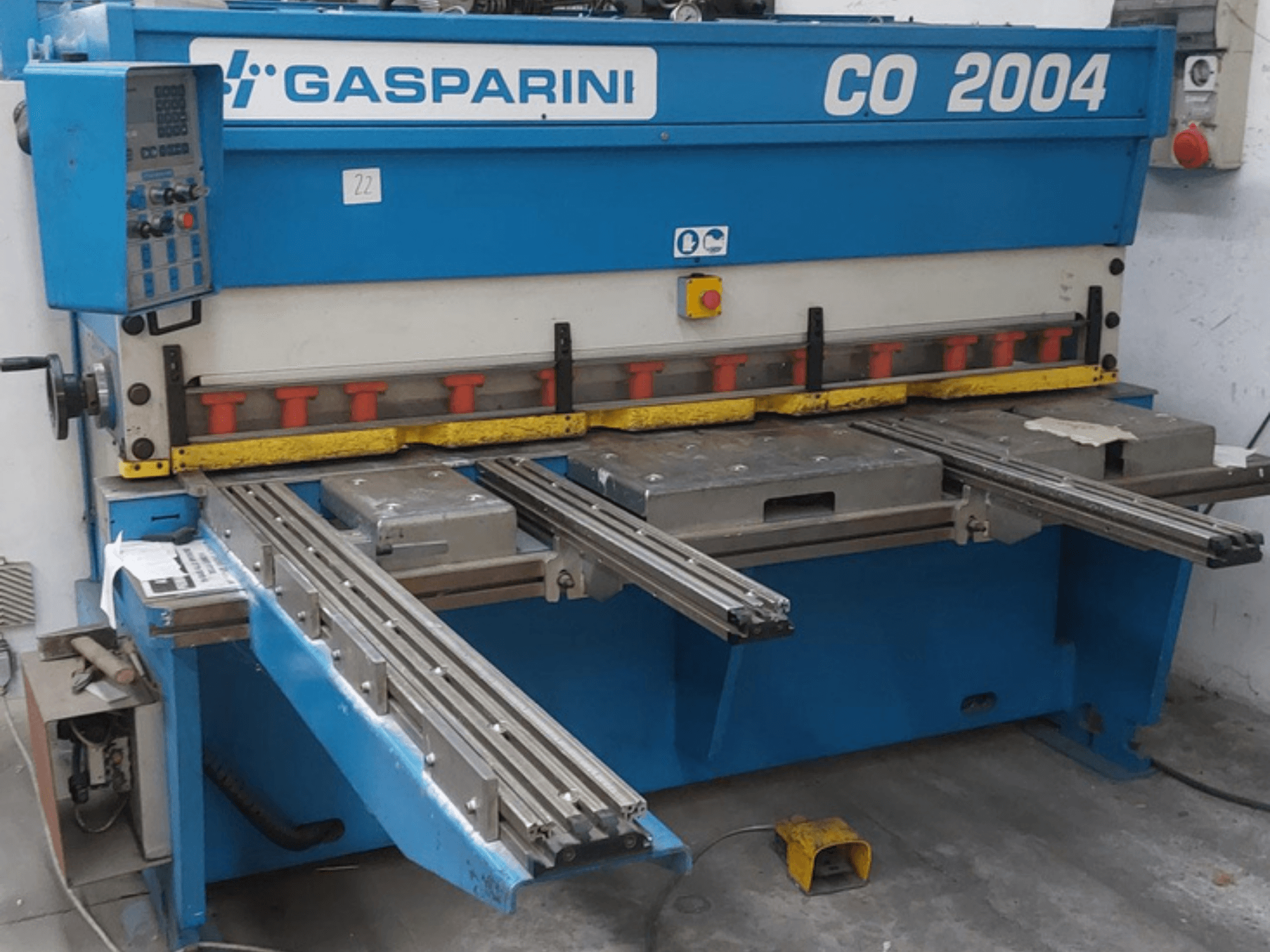 Hydraulický stříhací stroj GASPARINI CO/2004, pohled zepředu, s ovládacím panelem a kovovými řezacími stoly s posuvnými kolejnicemi.