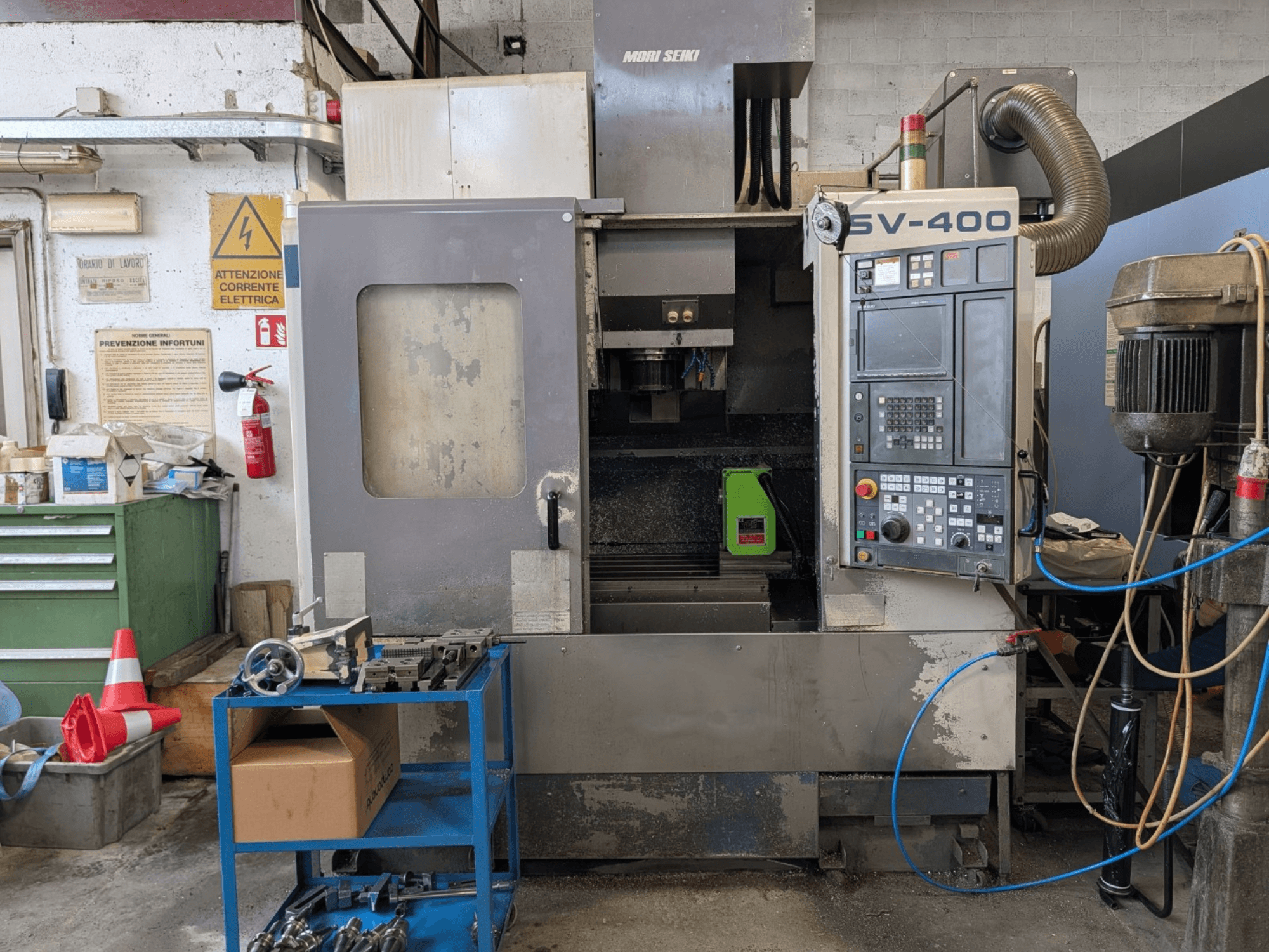 Vertikální obráběcí centrum MORI SEIKI SV-400 v dílně, boční pohled, na kterém je vidět ovládací panel a obráběcí stroje v blízkosti.
