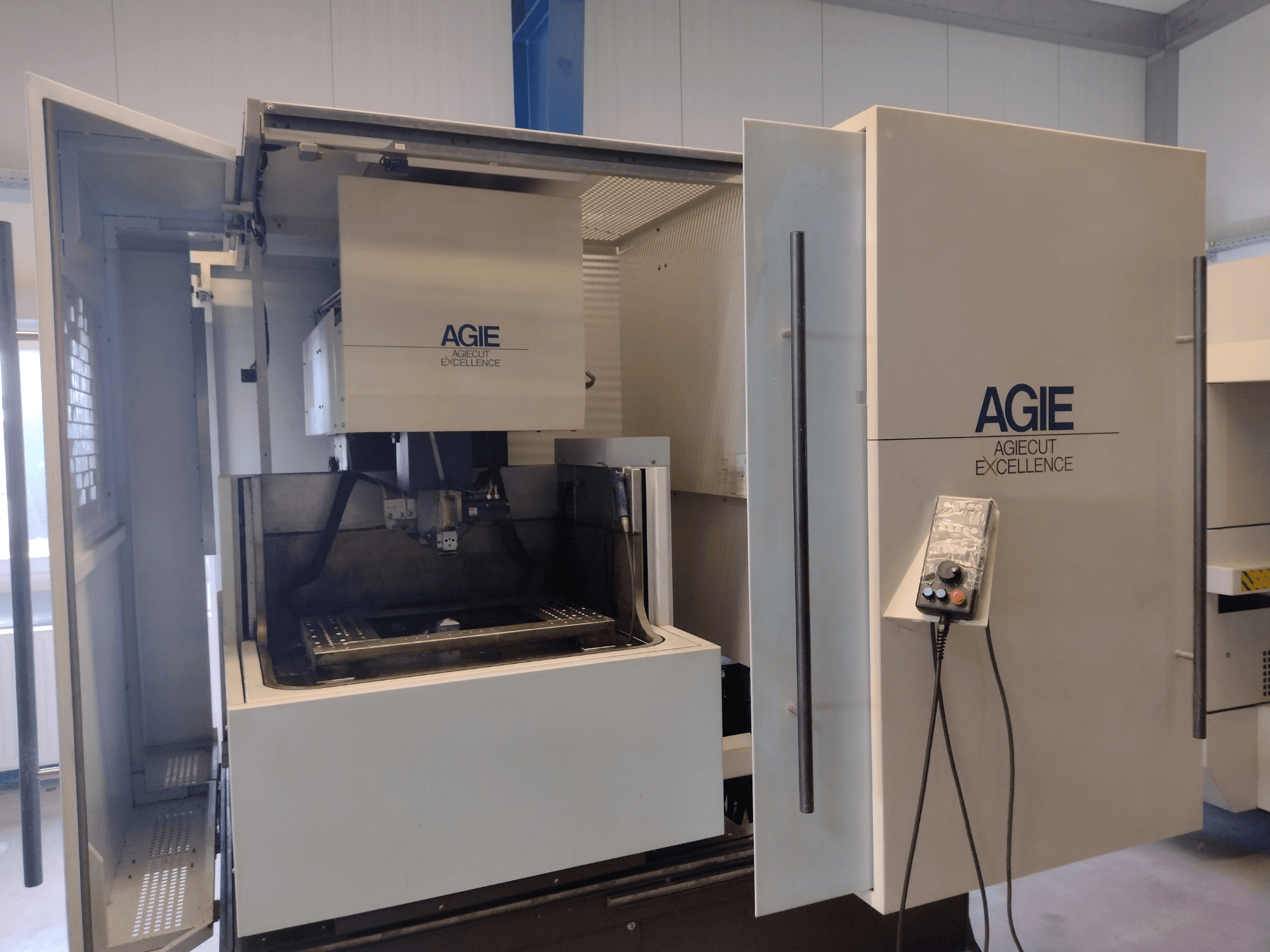 Stroj AGIE Progress pro 3-drátové elektroerozivní obrábění (EDM) v čelním pohledu, s otevřenou skříní, ovládacím panelem a řezací zónou.