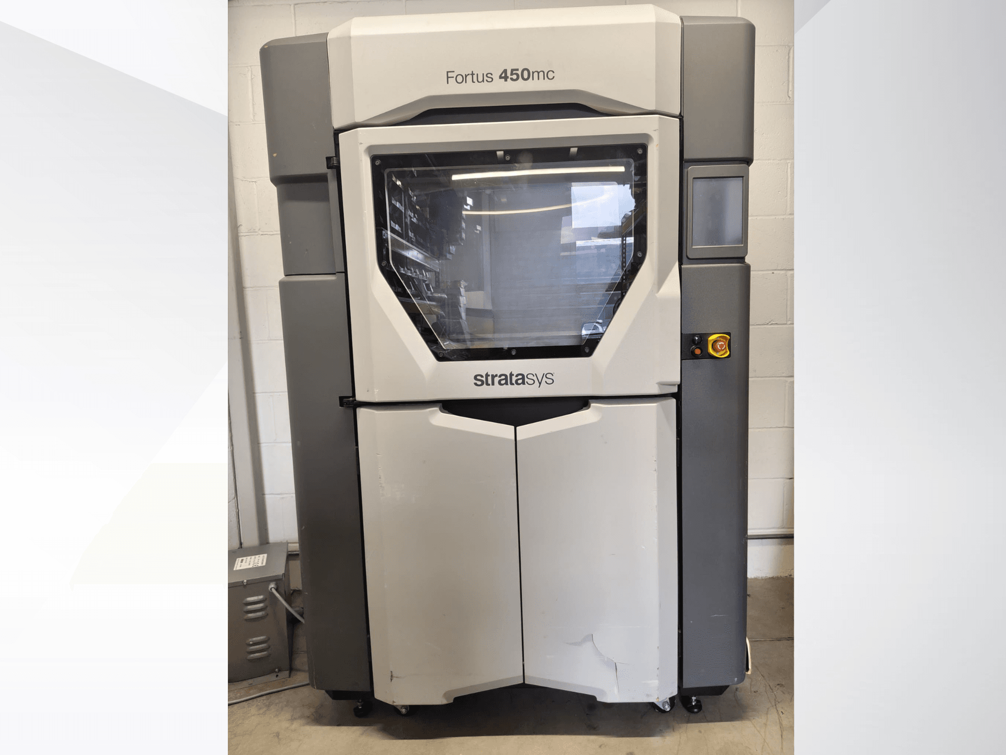 Stroj na zpracování plastů Stratasys Fortus 450mc, pohled zepředu, s velkým okénkem, ovládacím panelem a průmyslovým designem.