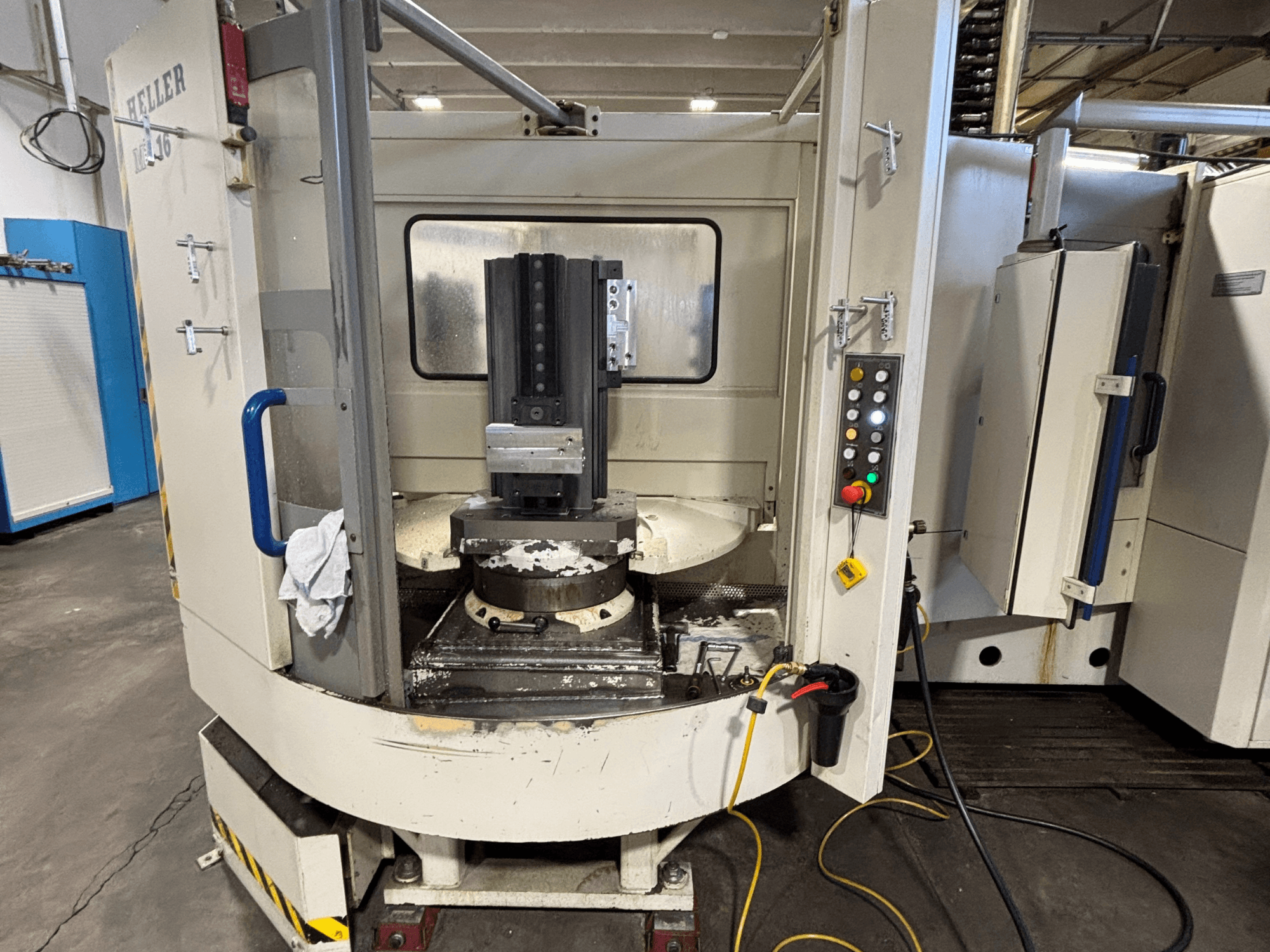 Obráběcí centrum Heller, model vertikální, čelní pohled zobrazující vřeteno, ovládací panel a pracovní stůl s připojeným zařízením.