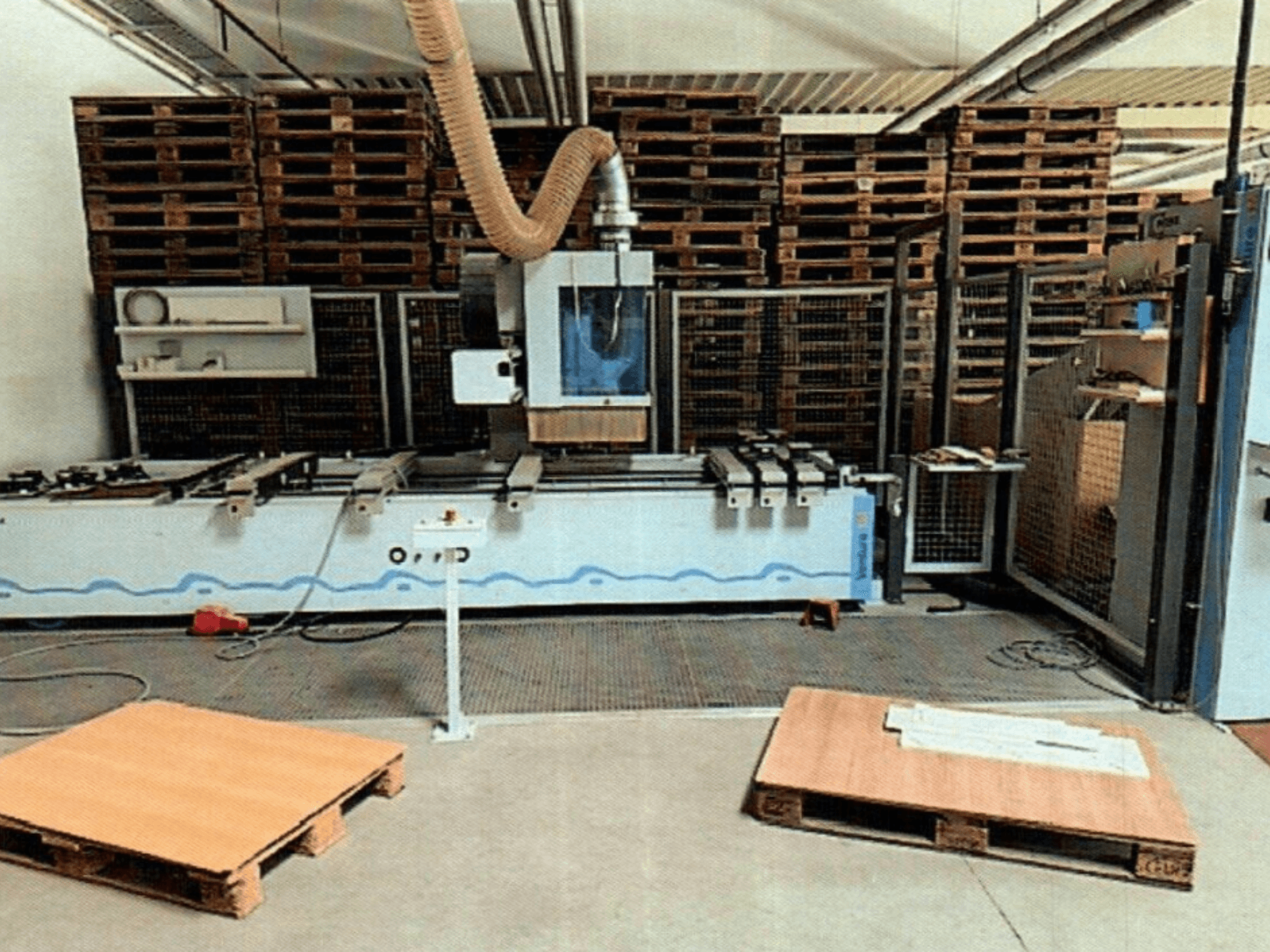 CNC obráběcí centrum na dřevo Weeke Venture 1M v dílně, pohled zepředu s viditelnými dřevěnými paletami a průmyslovým uspořádáním.