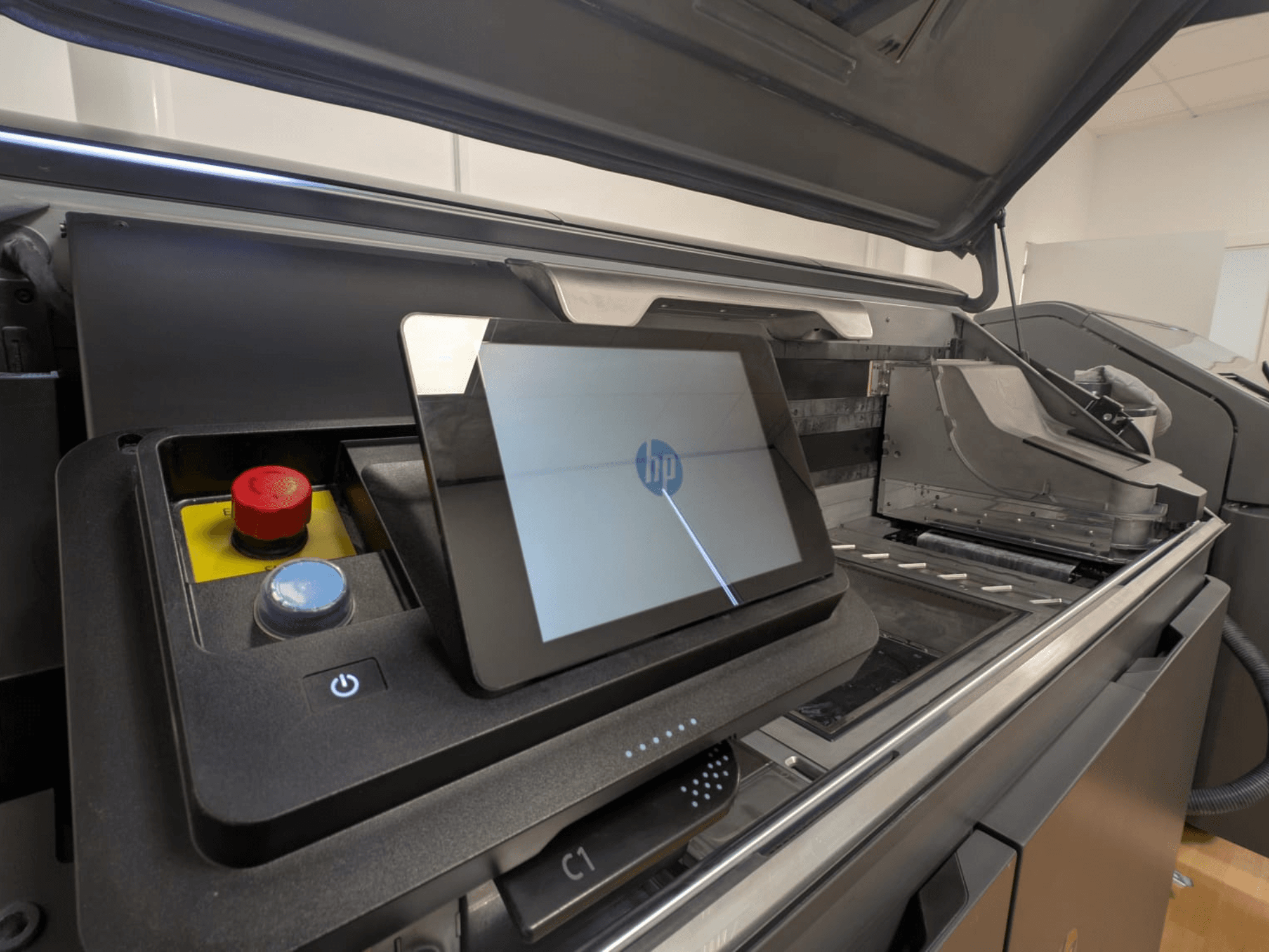 Ovládací panel tiskárny HP zobrazující displej tabletu, červená a modrá tlačítka a boční pohled na vnitřní součásti tiskárny.