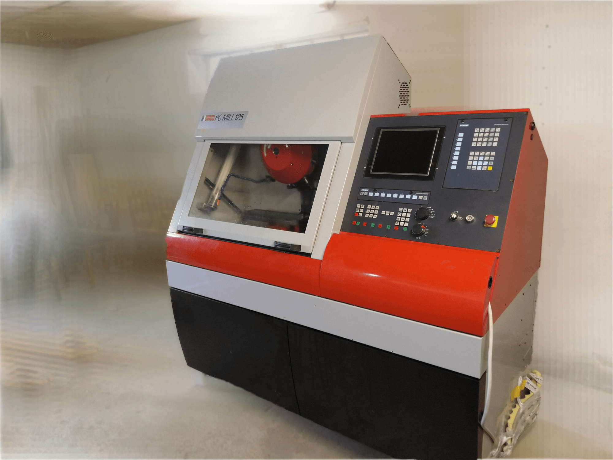 Vertikální obráběcí centrum EMCO PC MILL 125, pohled zepředu s ovládacím panelem a viditelnou oblastí obrábění.