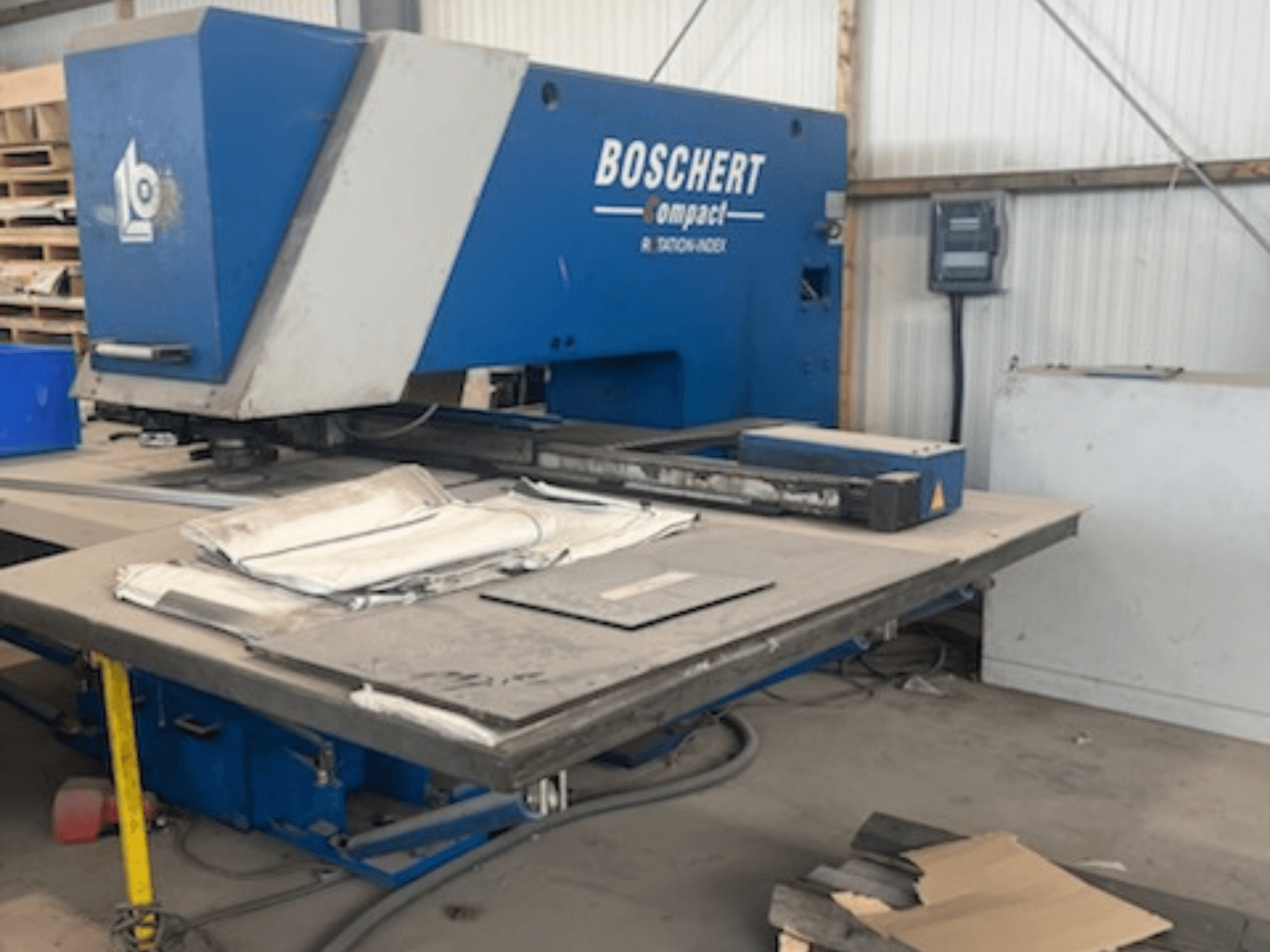 CNC děrovací stroj BOSCHERT COMPACT 1000 v dílně, pohled zepředu s plechy na stole.