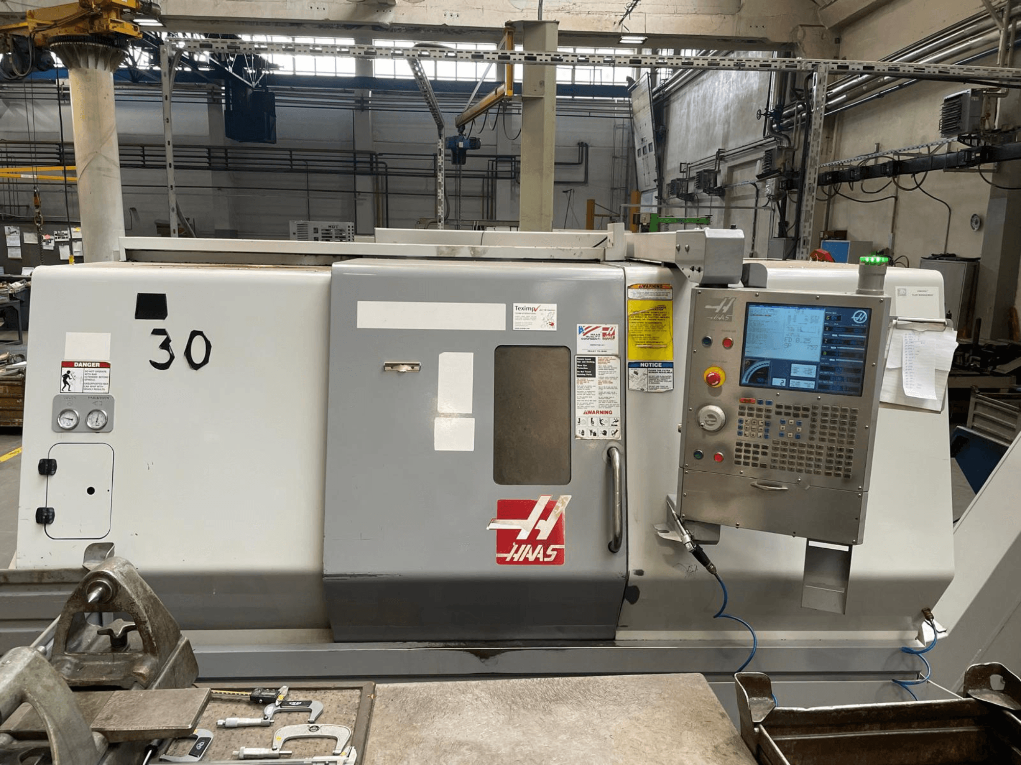 Pohled zepředu na horizontální soustruh Haas SL-30THE s digitálním ovládacím panelem, výstražnými štítky a číslem modelu 30.