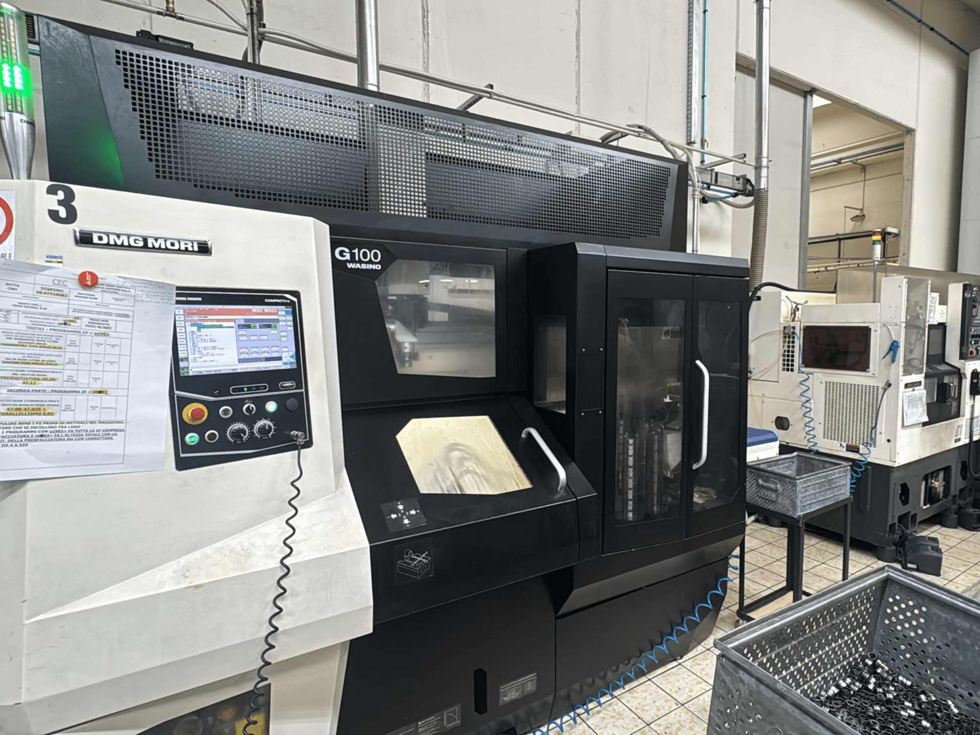 Stroj DMG MORI G100 v továrně, pohled zepředu, s digitálním ovládacím panelem a blízkými zásobníky na nástroje.