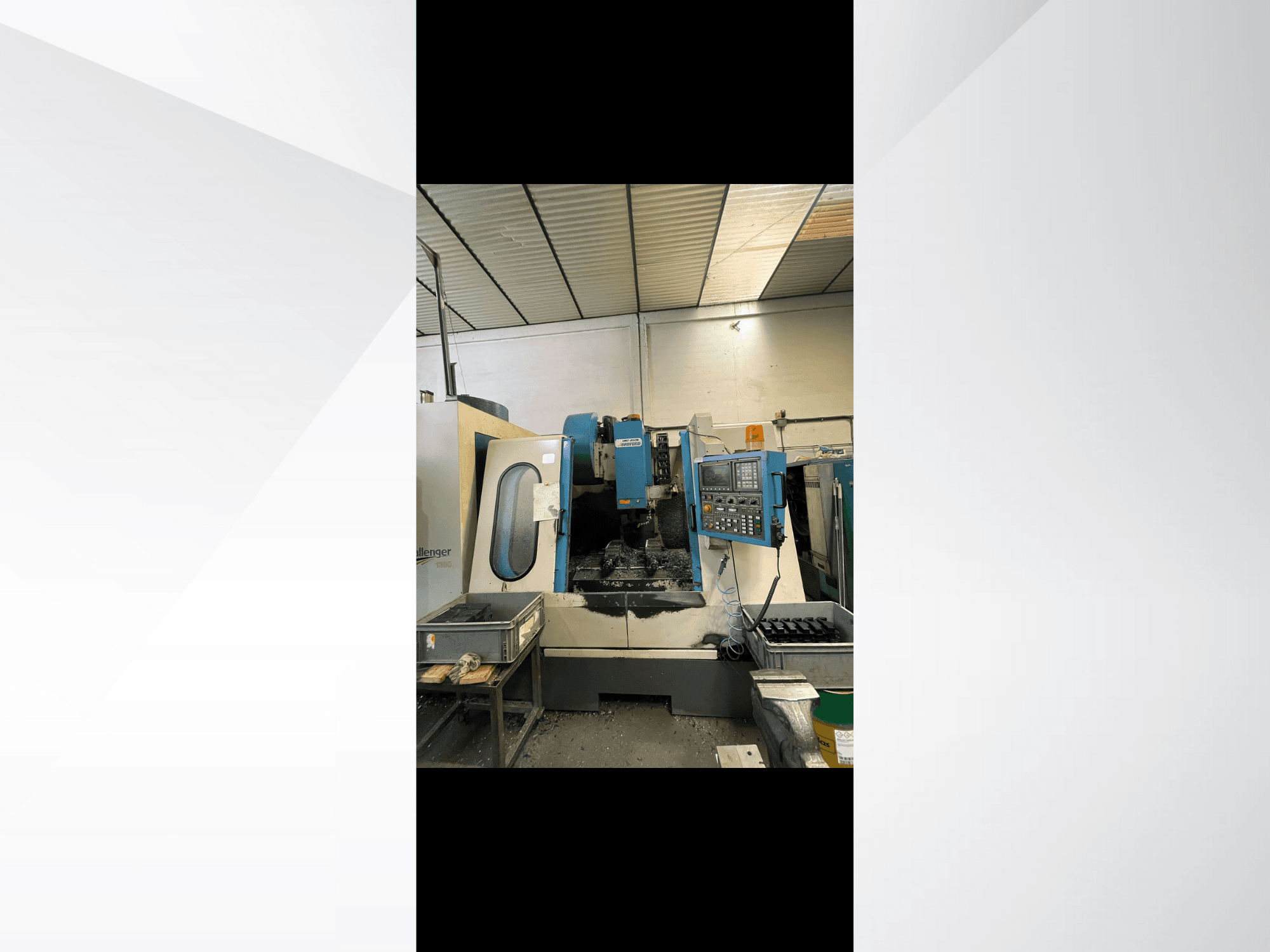 CNC stroj, model Challenger 1500, boční pohled na ovládací panel a pracovní prostor s kovovými hoblinami.