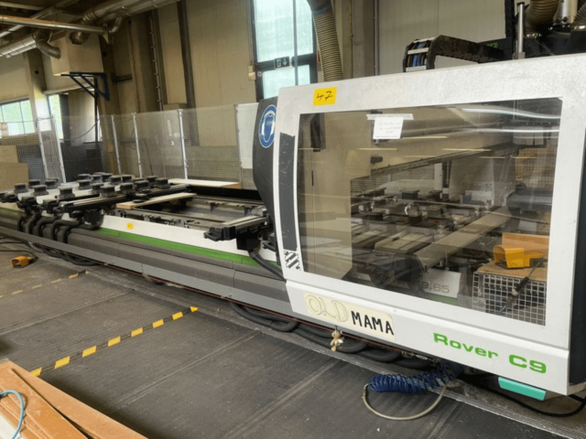 CNC frézka BIESSE Rover C 9.65 v dílně, boční pohled na ovládací panel a pracovní stůl se svorkami.