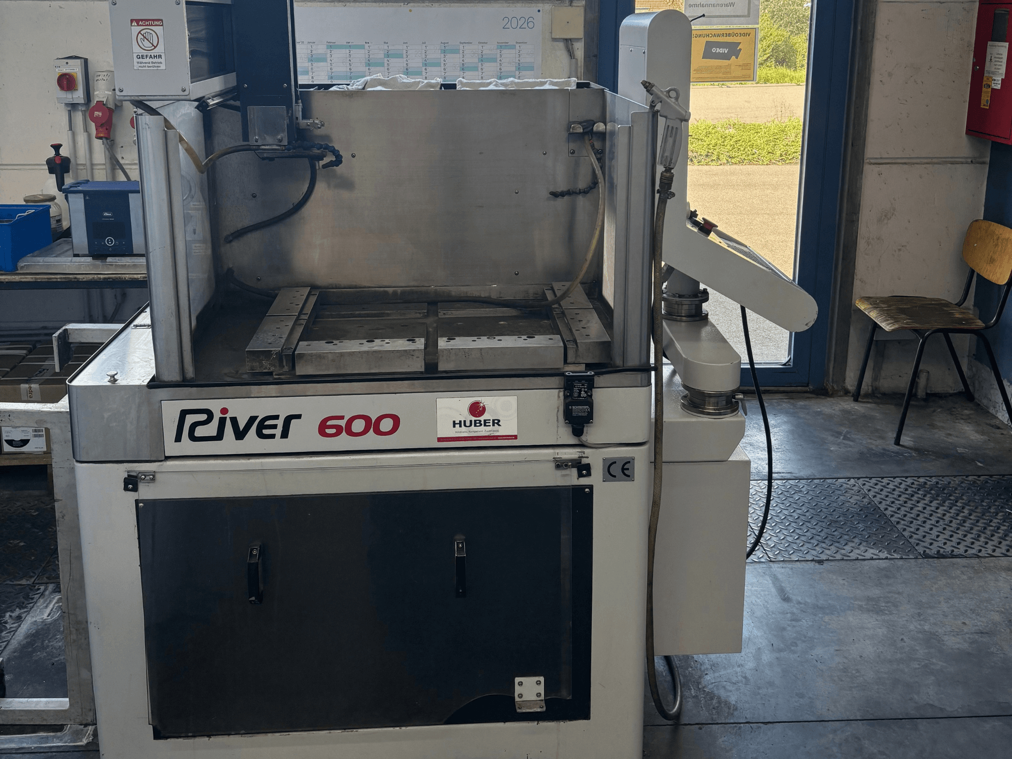 Elektroerozivní stroj HUBER River 600 CNC s hloubkovým výbojem, pohled zepředu, s částečně otevřenou pracovní komorou a ovládacím panelem.