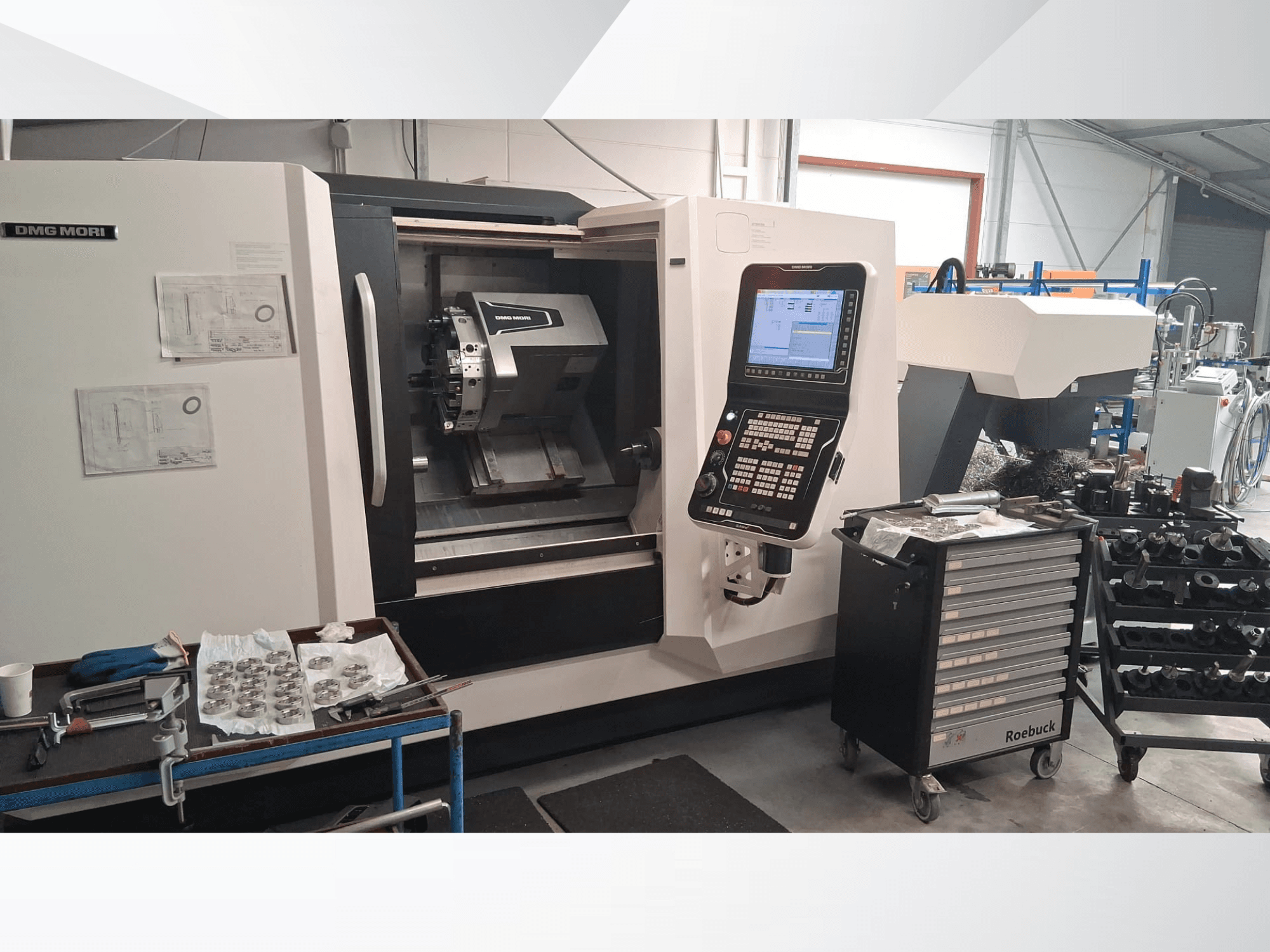 Horizontální soustruh DMG MORI CLX450 z čelního pohledu, s ovládacím panelem, pracovním prostorem, nástroji a kovovými díly.