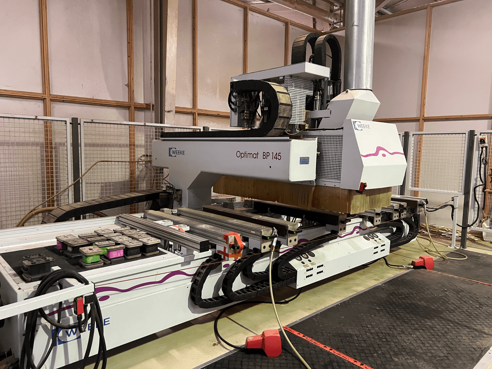 WEEKE Optimat BP 145 v továrně, ukázka CNC stroje s ovládacími tlačítky a kabely, pohled z boku.