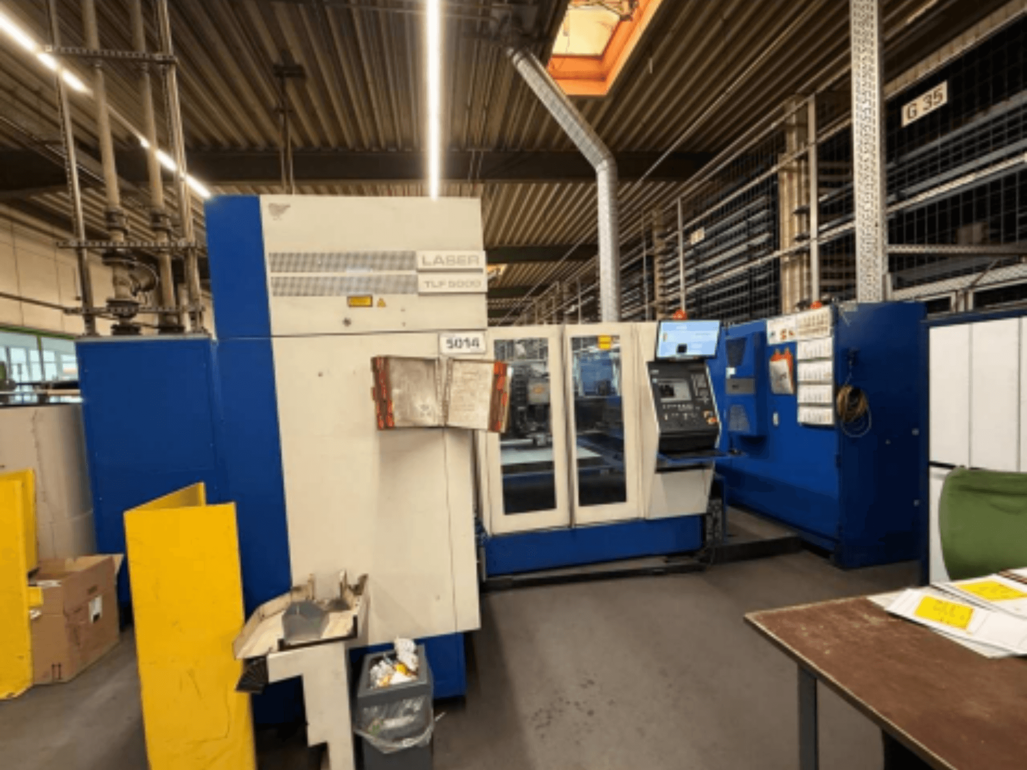 Pohled zepředu na laserový řezací stroj TRUMPF Trumatic L 3050 CO2, který ukazuje ovládací panel a provozní funkce v dílně.