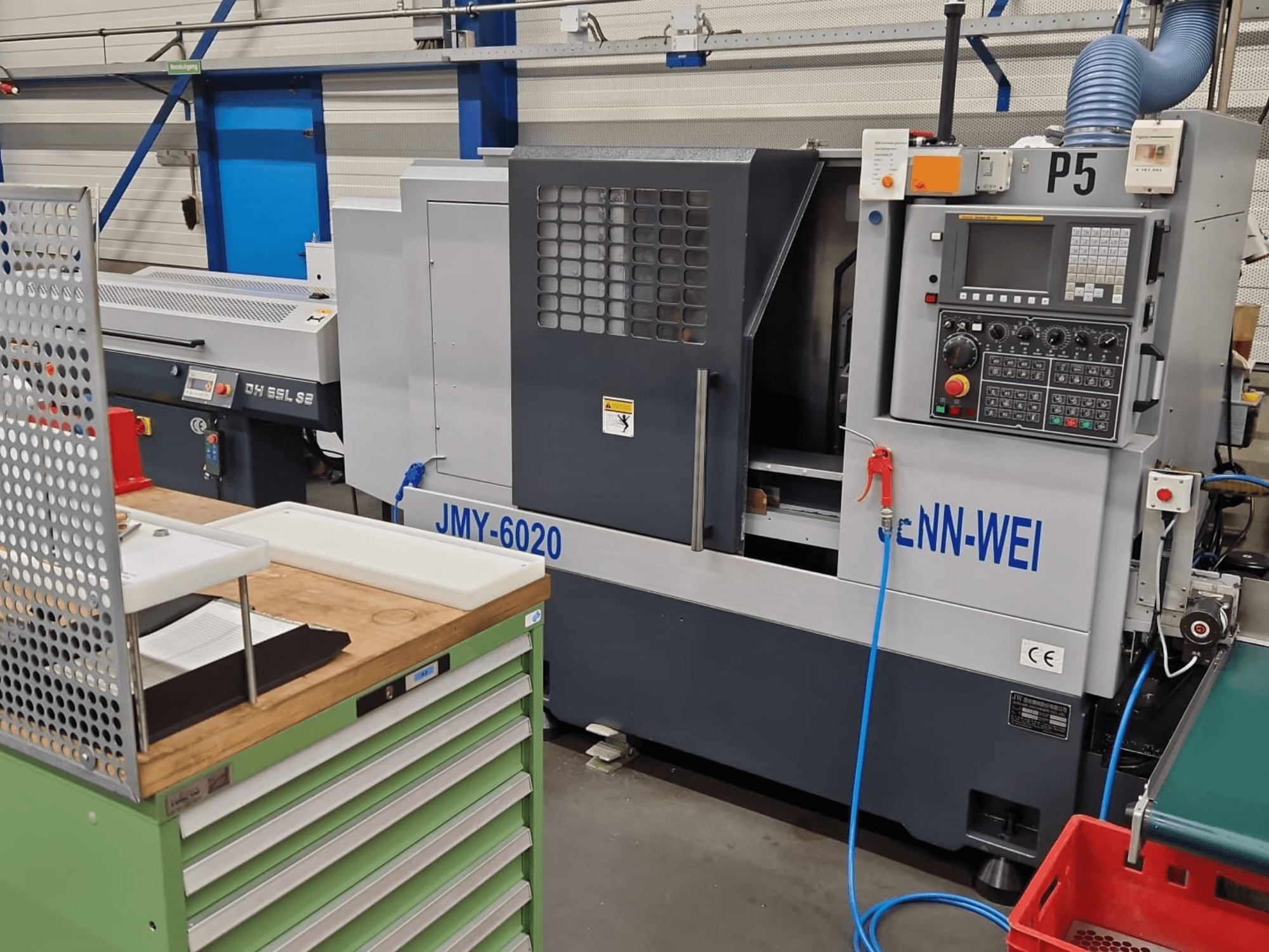 CNC soustruh, model JMY-6020 společnosti cNN-WEI, pohled zepředu. Obsahuje ovládací panel, nouzové zastavení a vedení chladicí kapaliny.