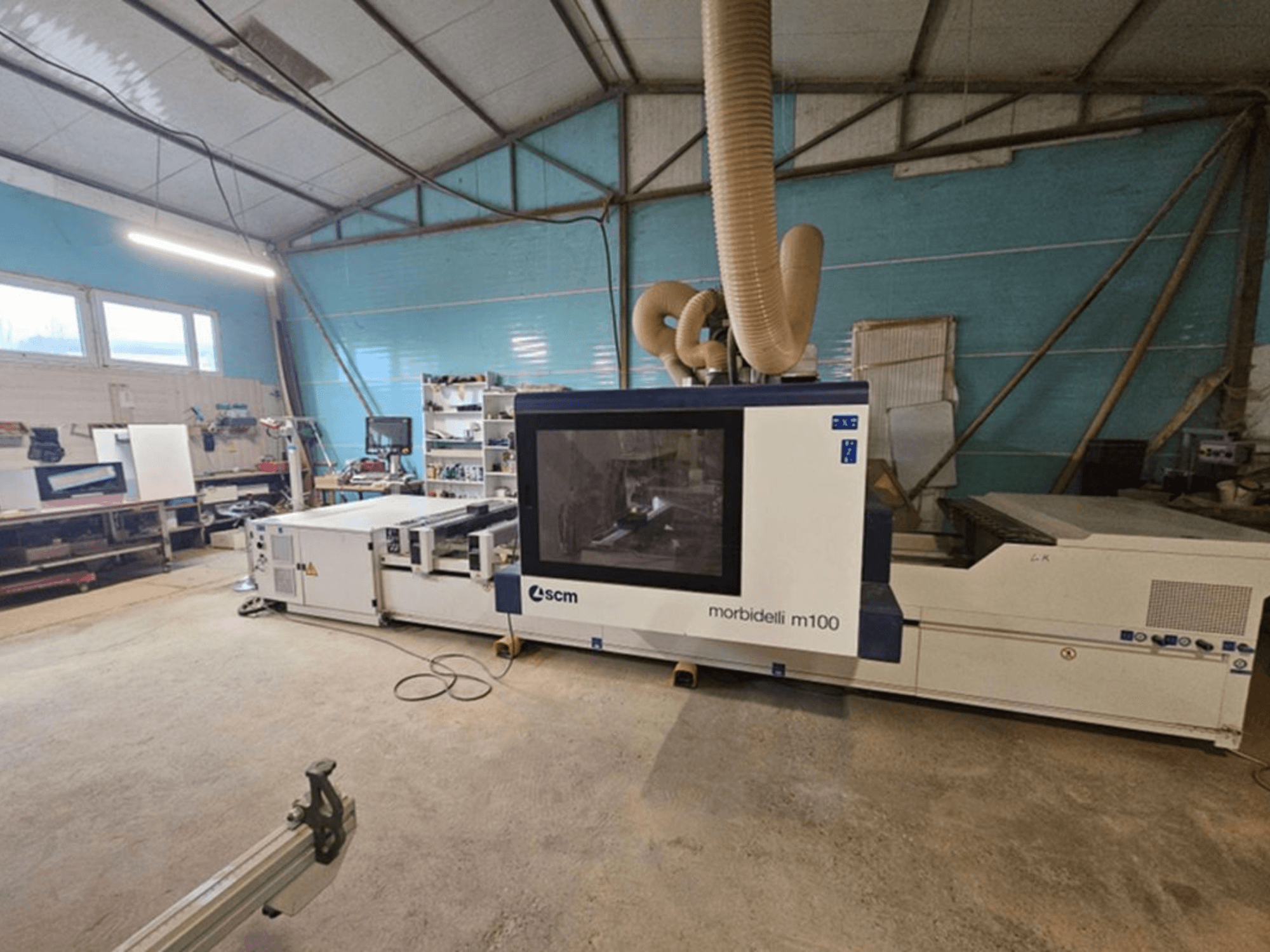CNC obráběcí centrum SCM MORBIDELLI M 100 v dílně, pohled zepředu s odsáváním prachu a vybavením okolního pracovního prostoru.