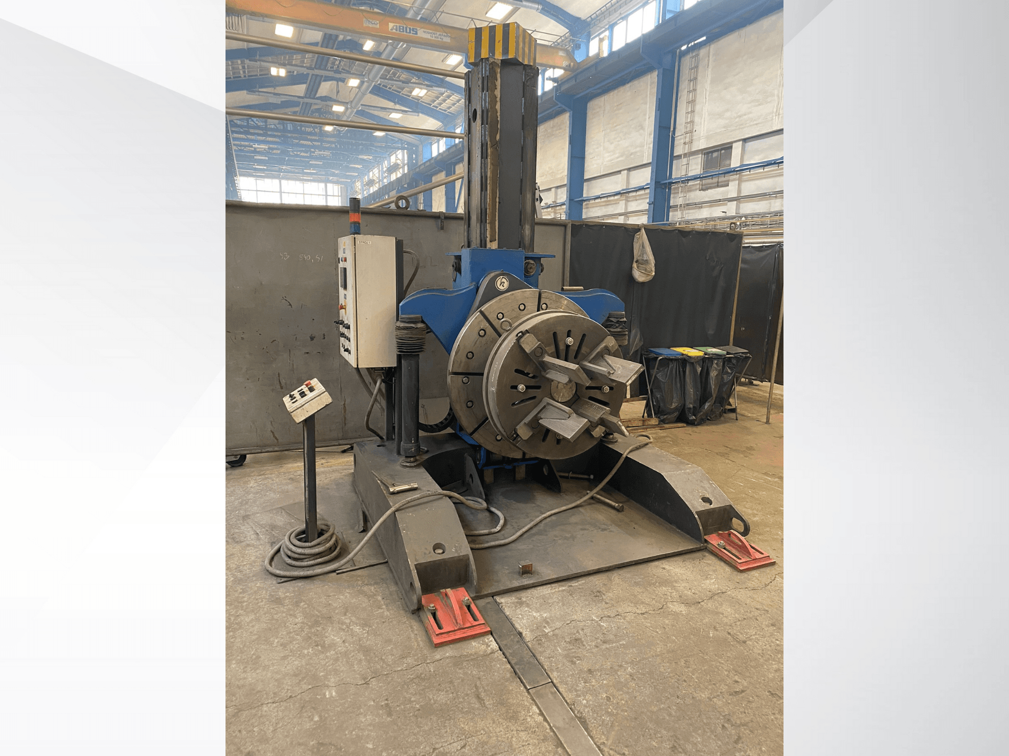 Modrý průmyslový soustruh s kruhovou otočnou hlavou a ovládacím panelem, boční pohled, v dílně.