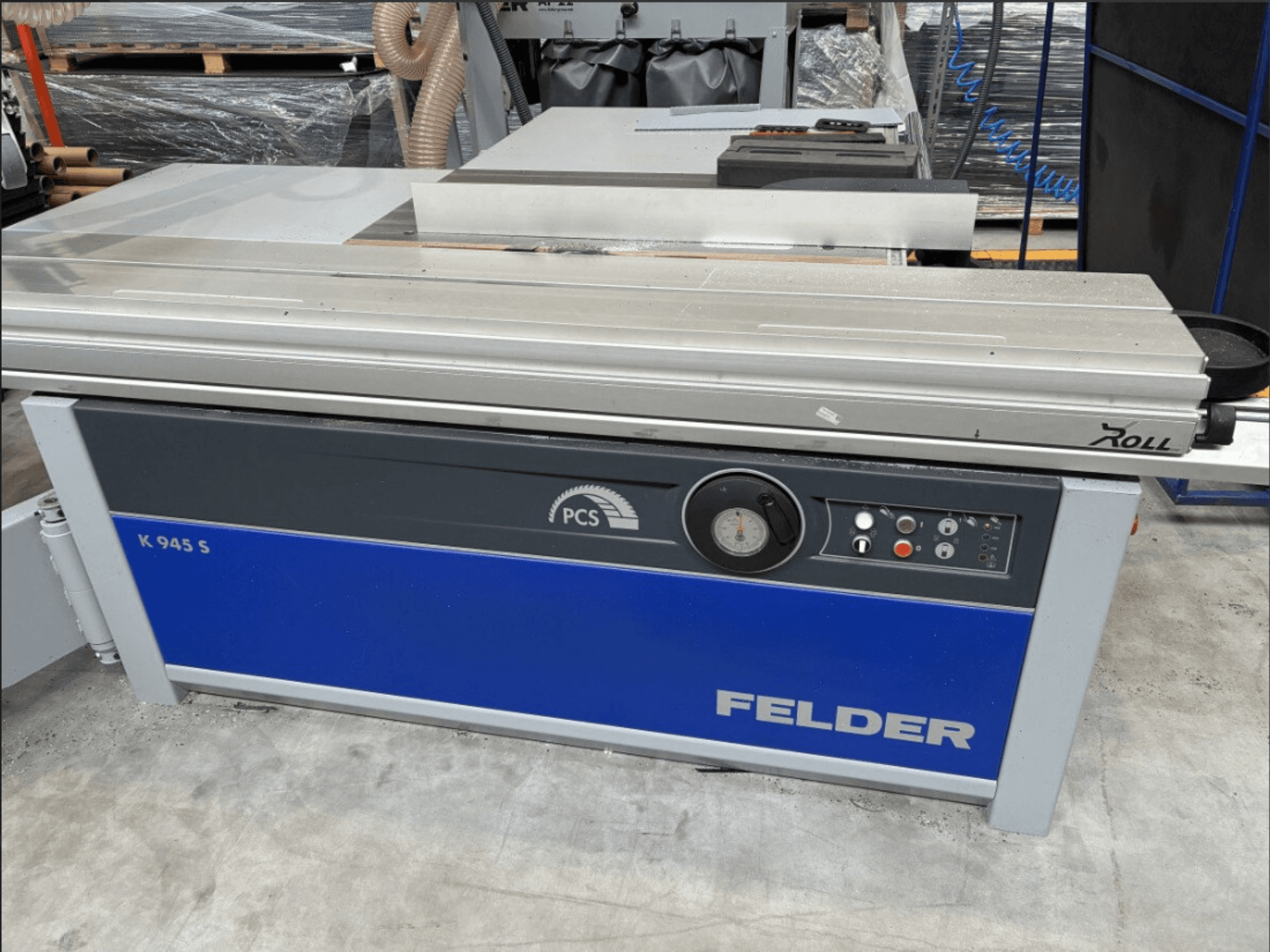 Plošná pila FELDER K 945 S, pohled zepředu na ovládací panel, pracovní stůl a bezpečnostní prvky, umístěná na podlaze dílny.