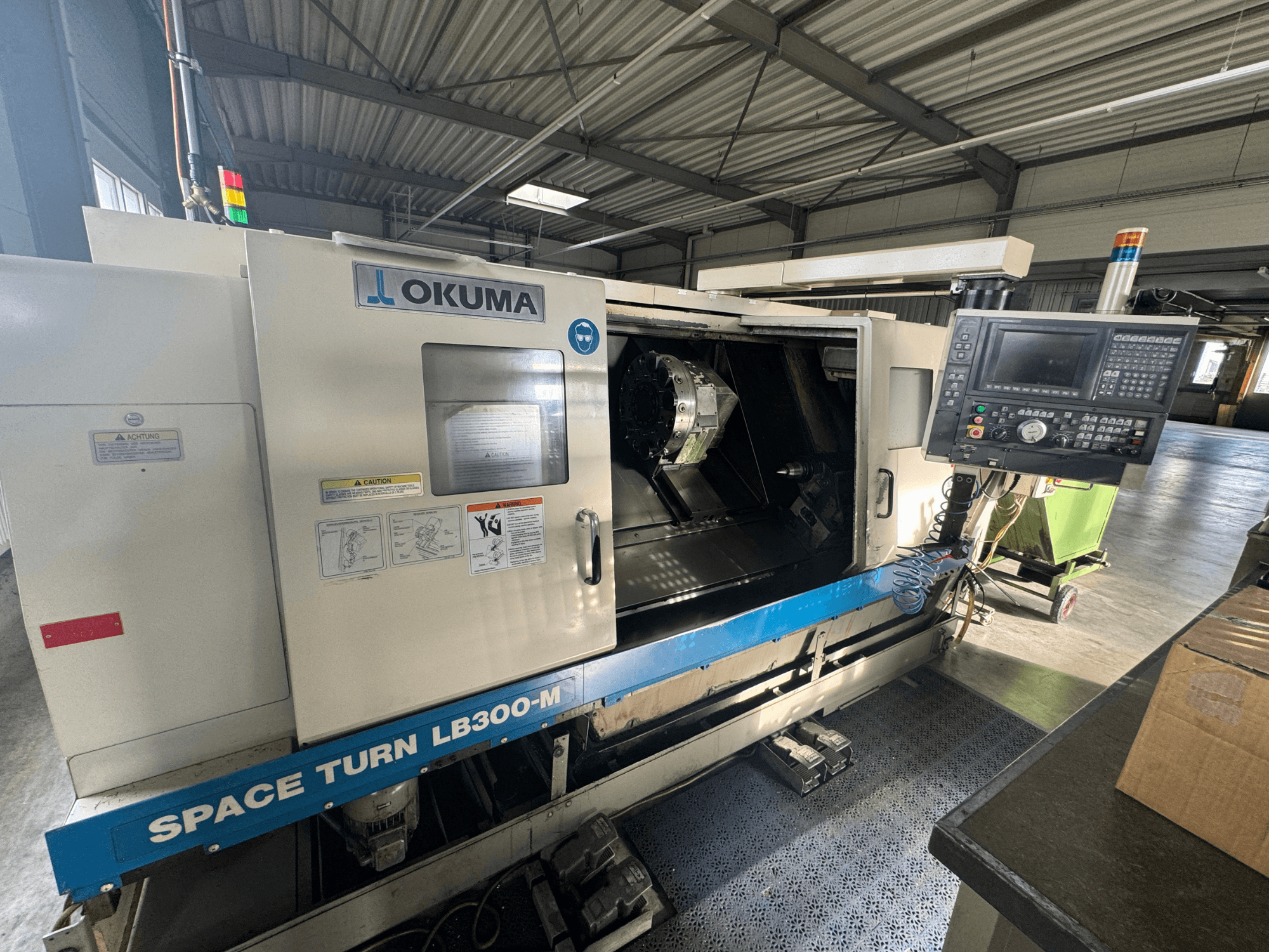 CNC soustruh Okuma Space Turn LB300-M v čelním pohledu, s ovládacím panelem a otevřenými dvířky odhalujícími vnitřní obráběcí prostor.