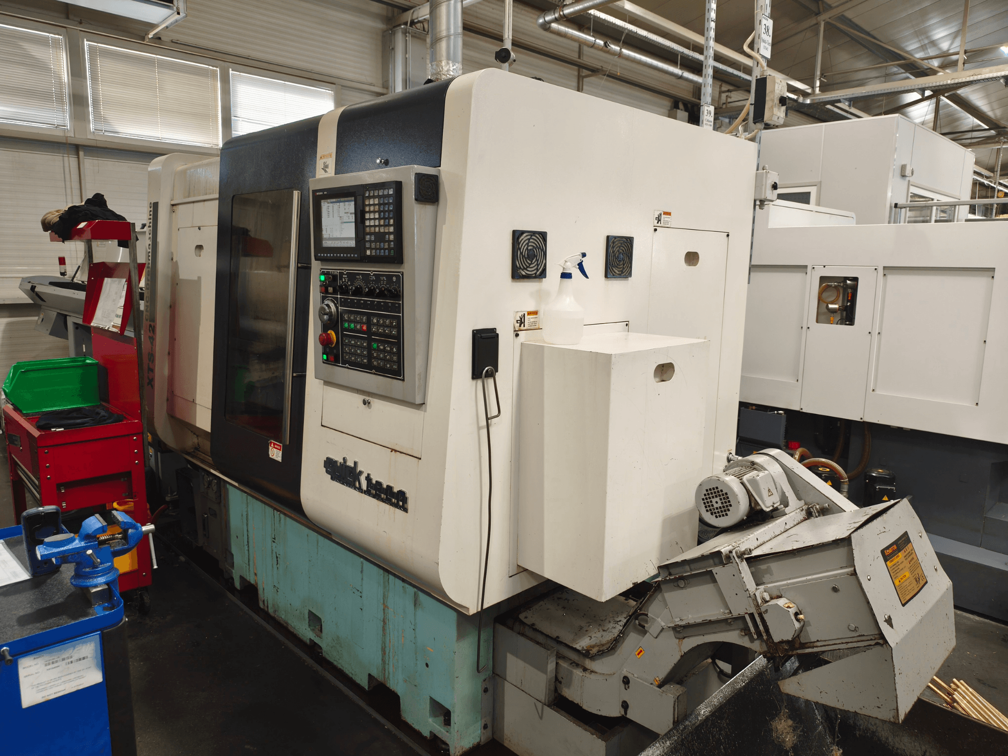 Pohled zepředu na horizontální soustruh Quick-Tech XTS-42 s ovládacím panelem a nádržkou na chladicí kapalinu.