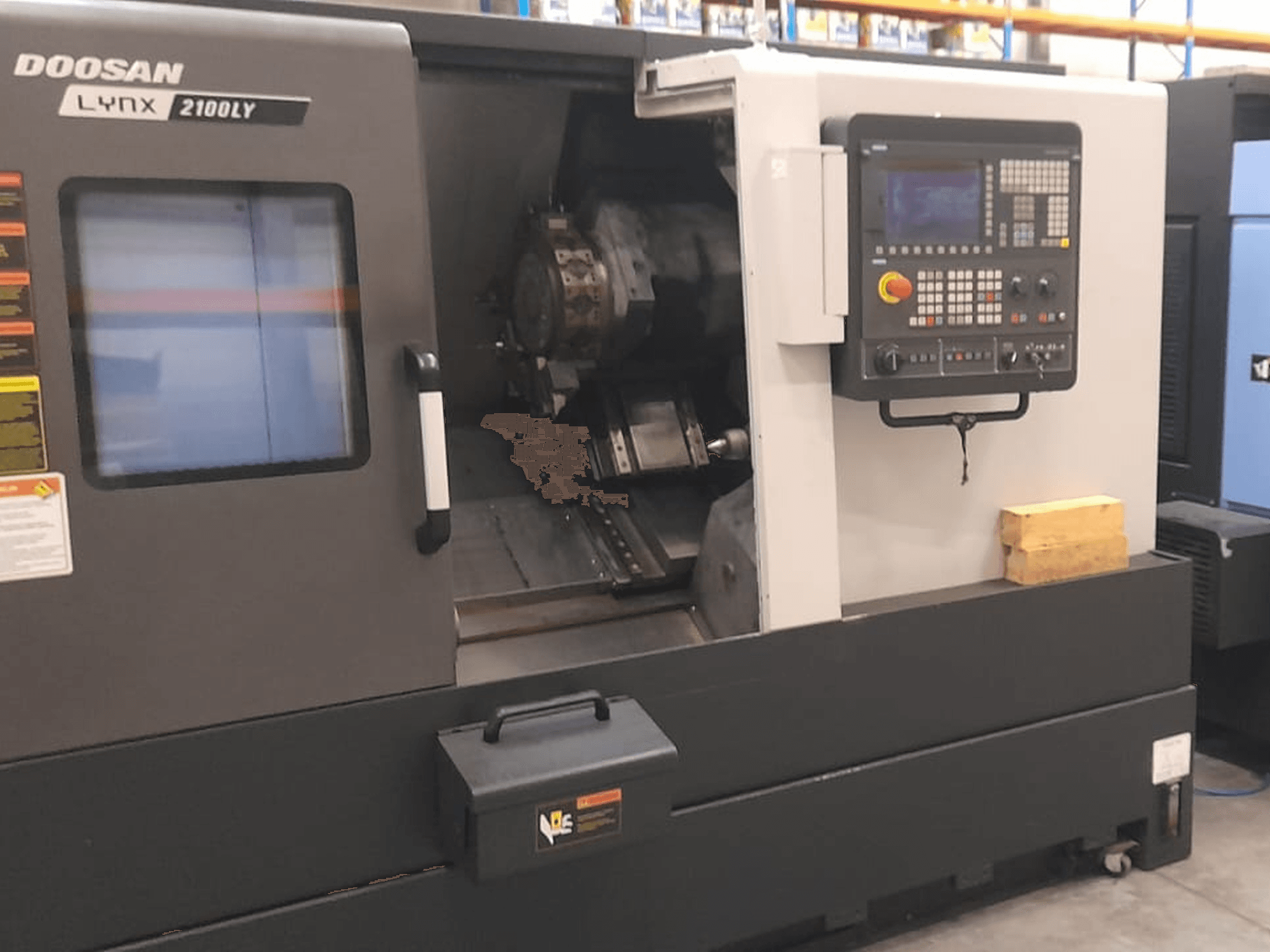 CNC soustruh Doosan Lynx 2100LY, čelní pohled zobrazující ovládací panel, držák nástrojů a vnitřní pracovní prostor; viditelné technické štítky.