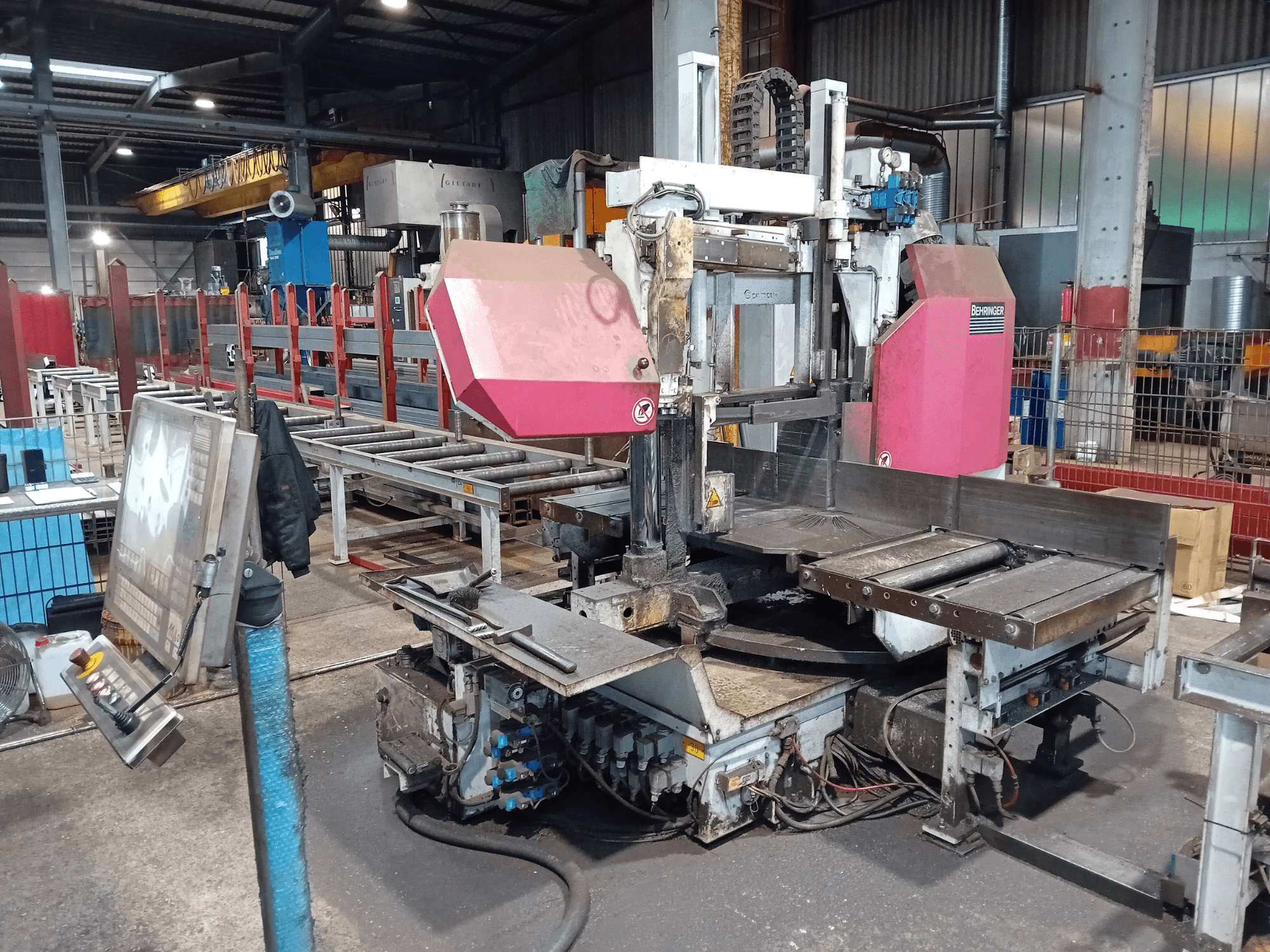 Pásová pila Behringer v továrně, pohled zepředu, s velkým řezacím kotoučem a ovládacím panelem s tlačítky.