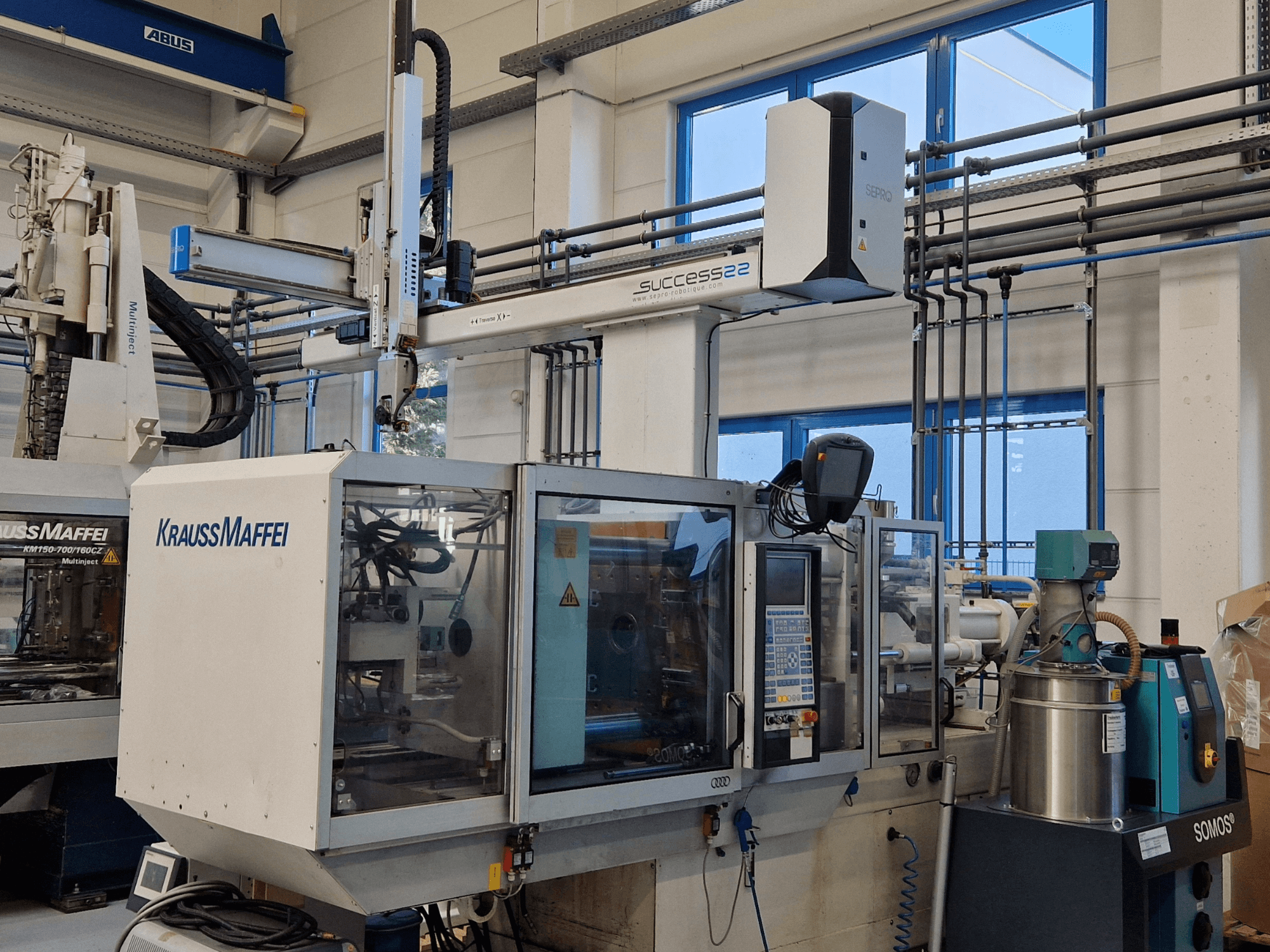 Vstřikovací stroj KraussMaffei Success 22 s ovládacím panelem, pohled zepředu v továrním prostředí.