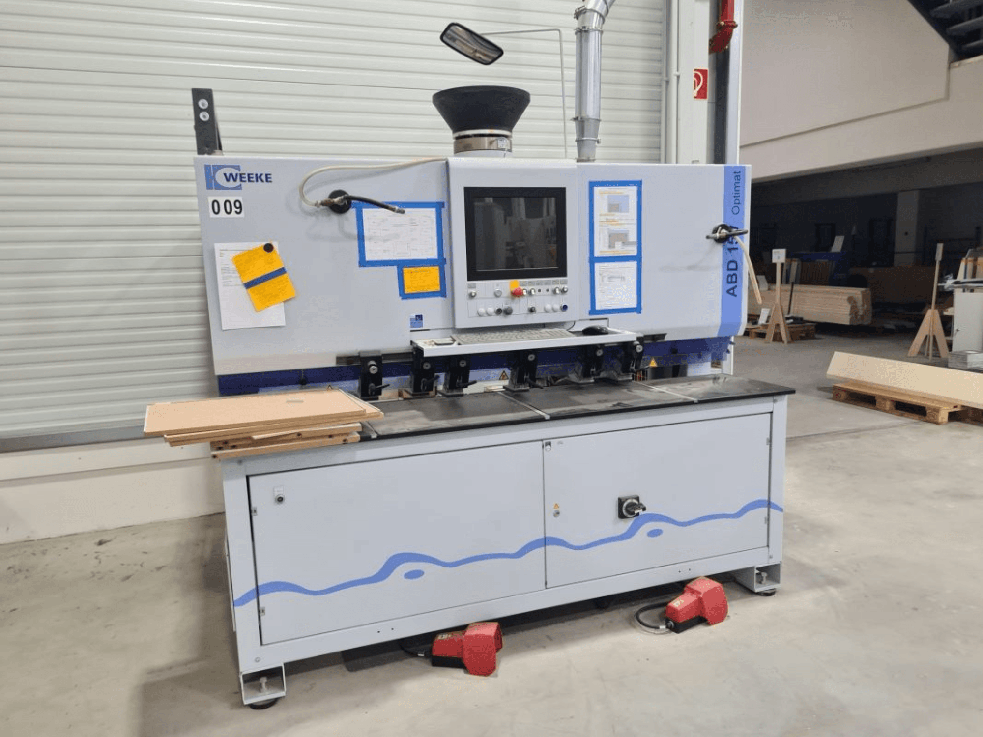 Vícevřetenová vrtačka HOMAG WEEKE OPTIMAT ABD150, pohled zepředu, zobrazeny ovládací prvky a naskládané dřevěné desky.