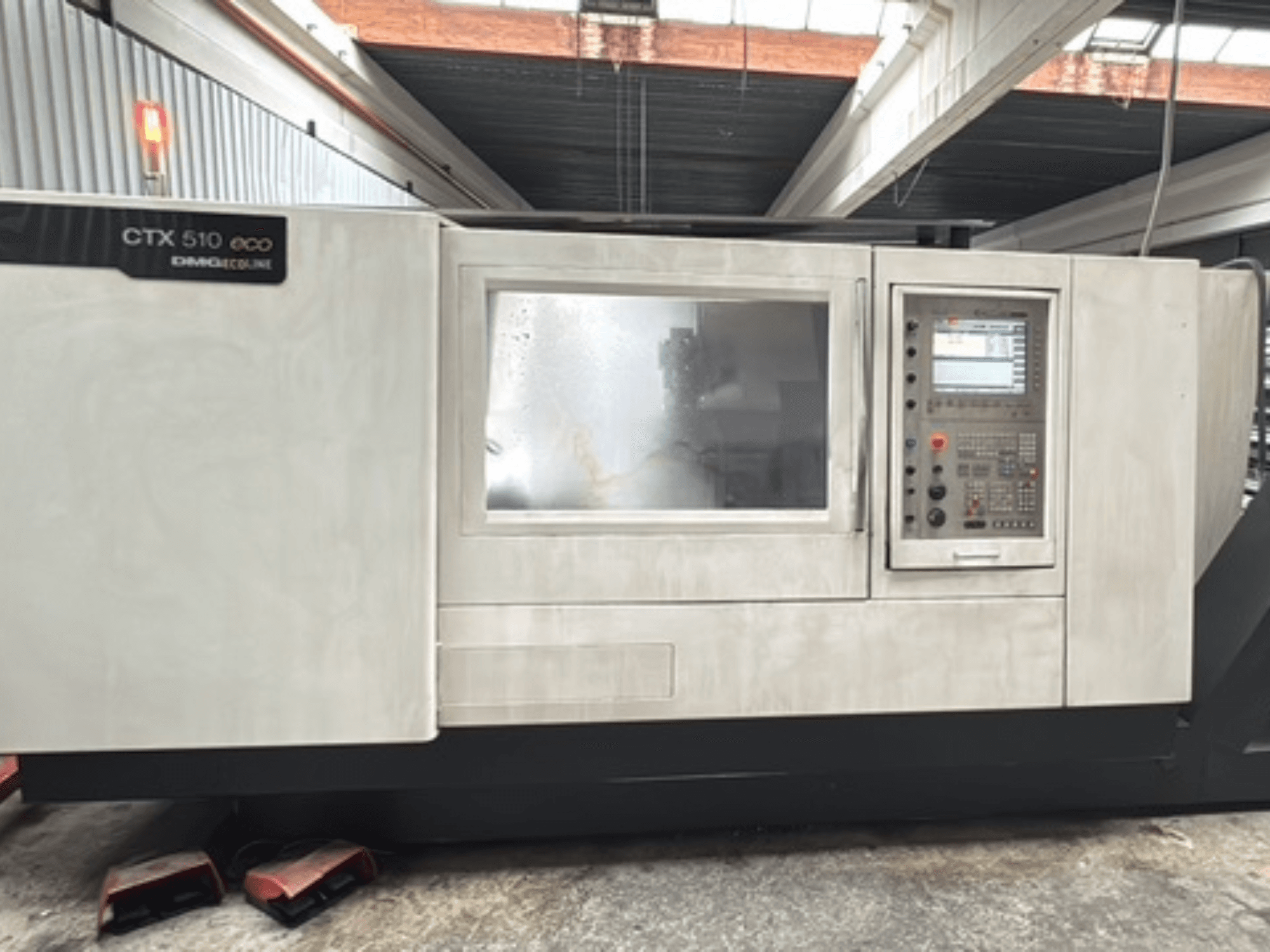 Horizontální soustruh DMG CTX 510 ecoline, pohled zepředu, na kterém je vidět ovládací panel a okénko na těle stroje.