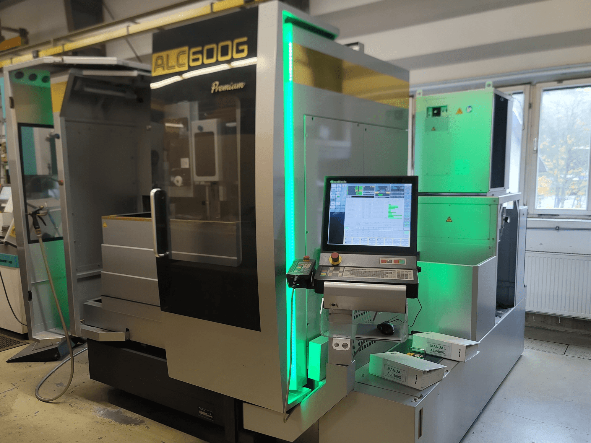 Drátový elektroerozivní stroj Sodick ALC600G Premium, pohled zepředu na ovládací panel a osvětlené vnější detaily.