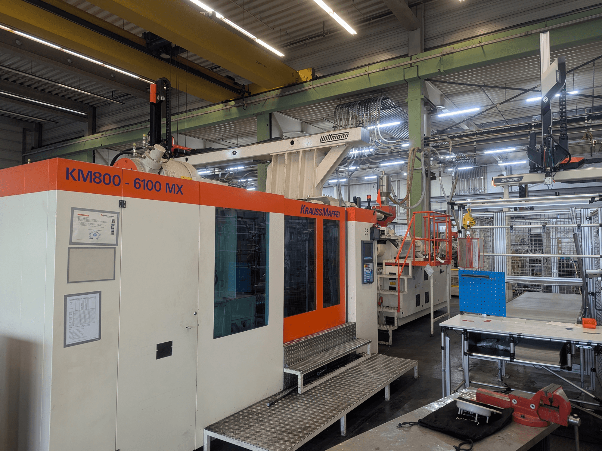 Hydraulický vstřikovací stroj Krauss Maffei KM 800-6100MX, pohled zepředu, ukázka ovládacího panelu a průmyslového nastavení.