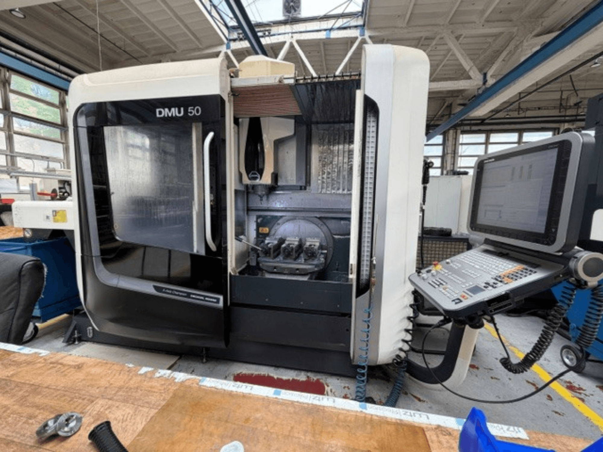 Vertikální obráběcí centrum DMG MORI DMU 50 3. generace zachycené zepředu, s otevřenými dvířky, viditelným ovládacím panelem CNC a pracovním prostorem uvnitř.