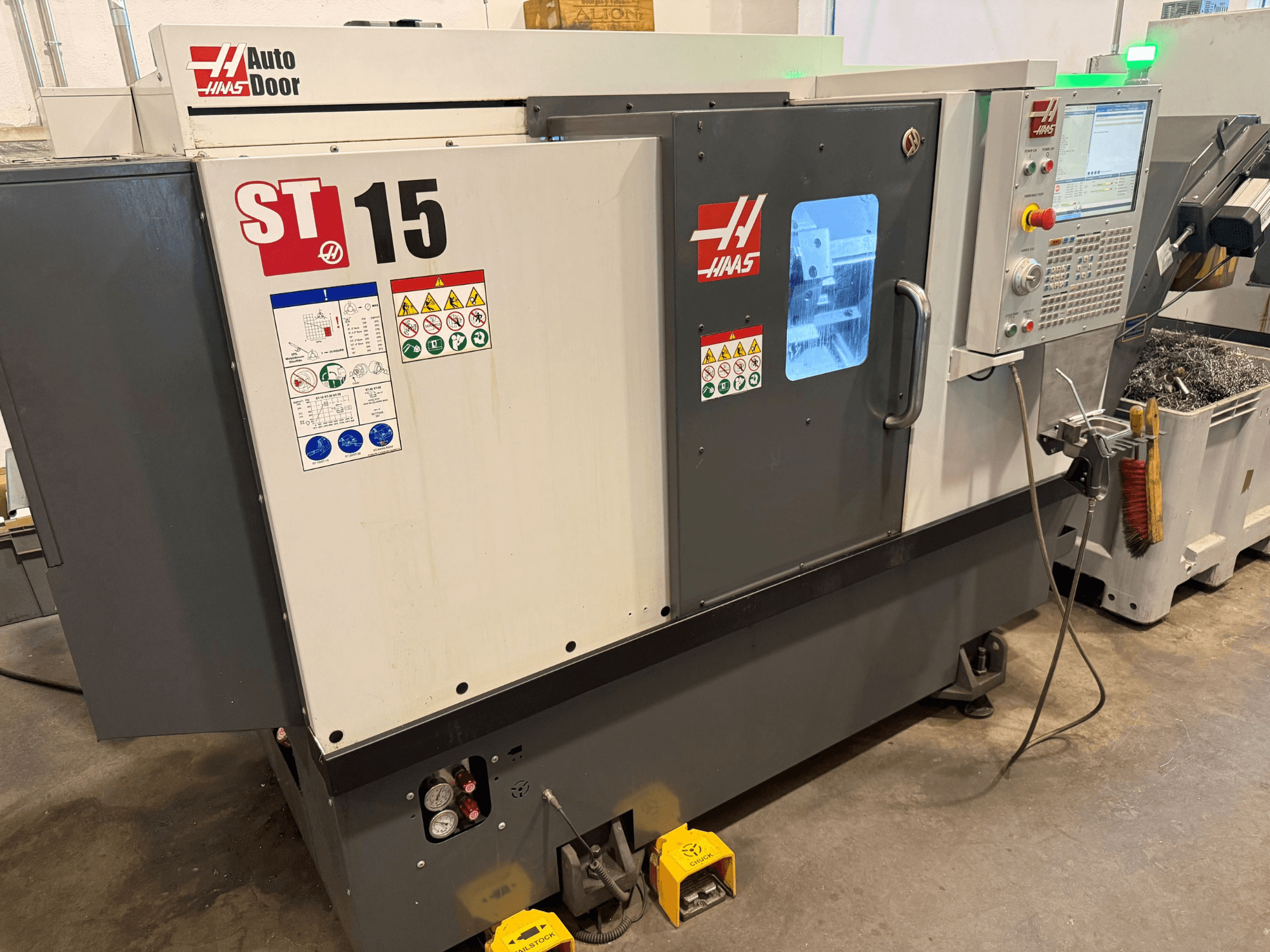 Horizontální soustruh HAAS ST 15, pohled zepředu s ovládacím panelem, automatickými dvířky a viditelnými technickými ukazateli.