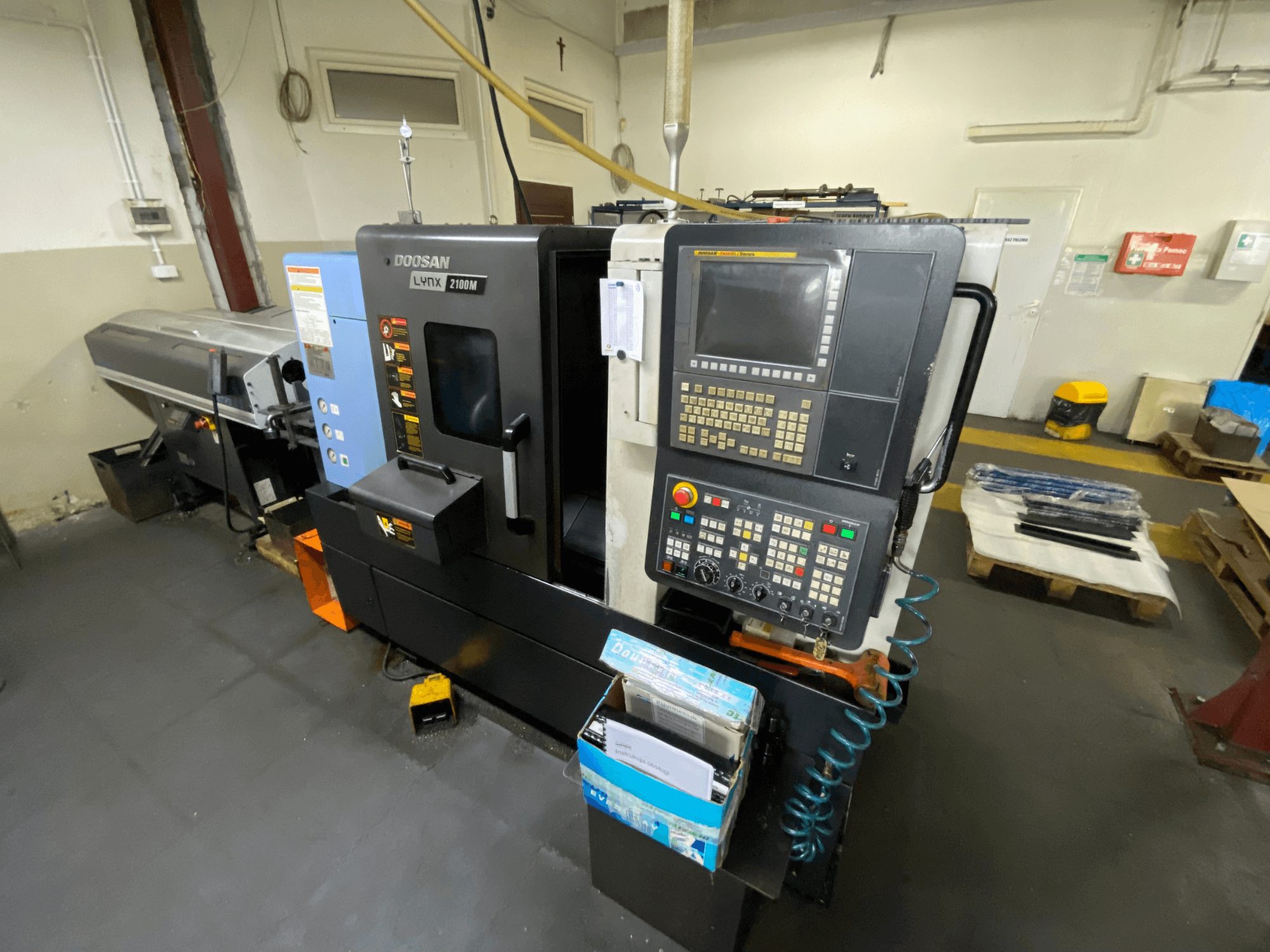 Horizontální soustruh DOOSAN LYNX 2100MA při pohledu z boku, s ovládacím panelem, nástroji a pracovním prostorem.