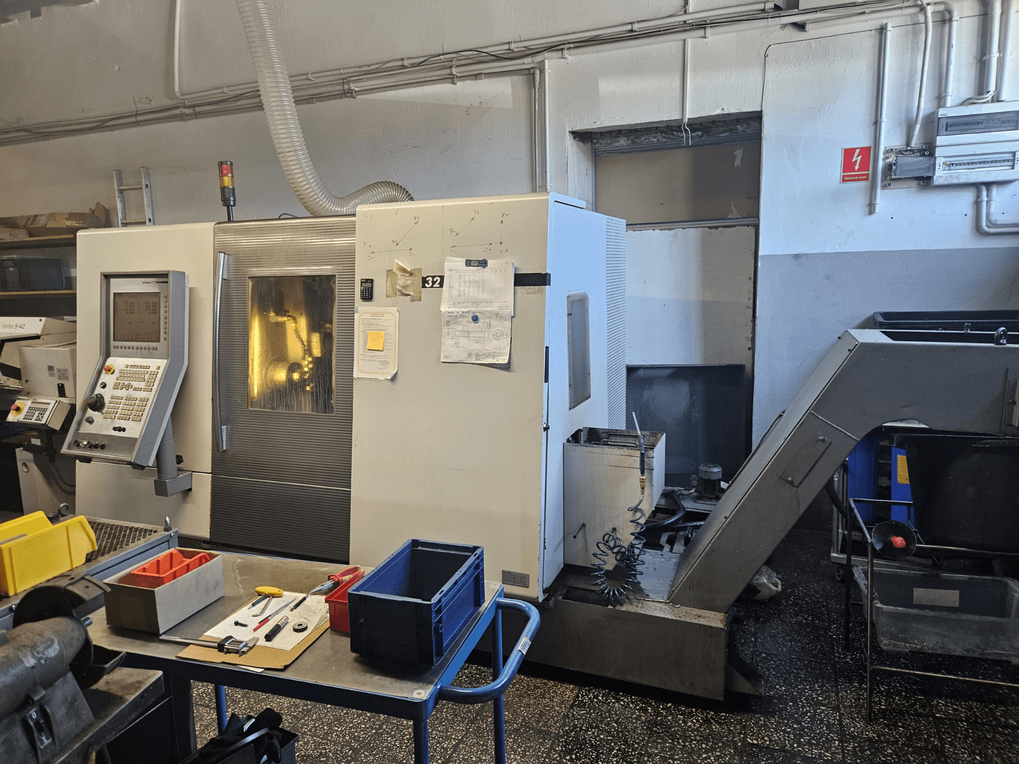 Vícevřetenový soustruh DMG GILDEMEISTER Sprint 32 linear, pohled zepředu v dílně, s viditelným ovládacím panelem a nástroji.