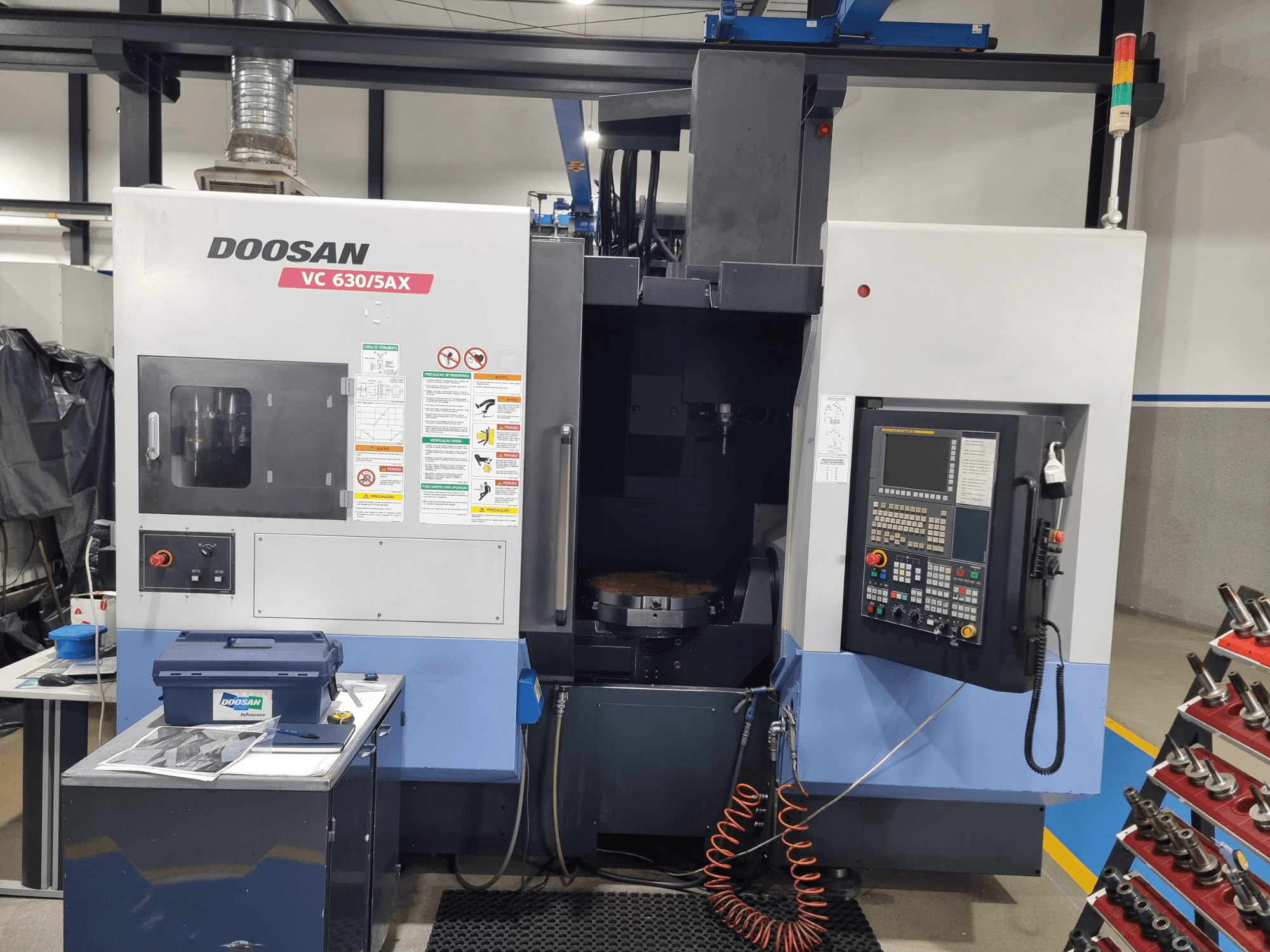 Univerzální obráběcí centrum DOOSAN VC 630/5AX, pohled zepředu znázorňující ovládací panel, obráběcí prostor a bezpečnostní prvky.